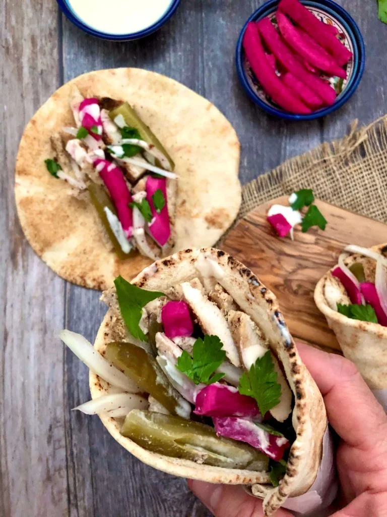 Grilled Chicken Shawarma served on Arabic bread wrap covered with Tahini sauce, pickles, and red onions.