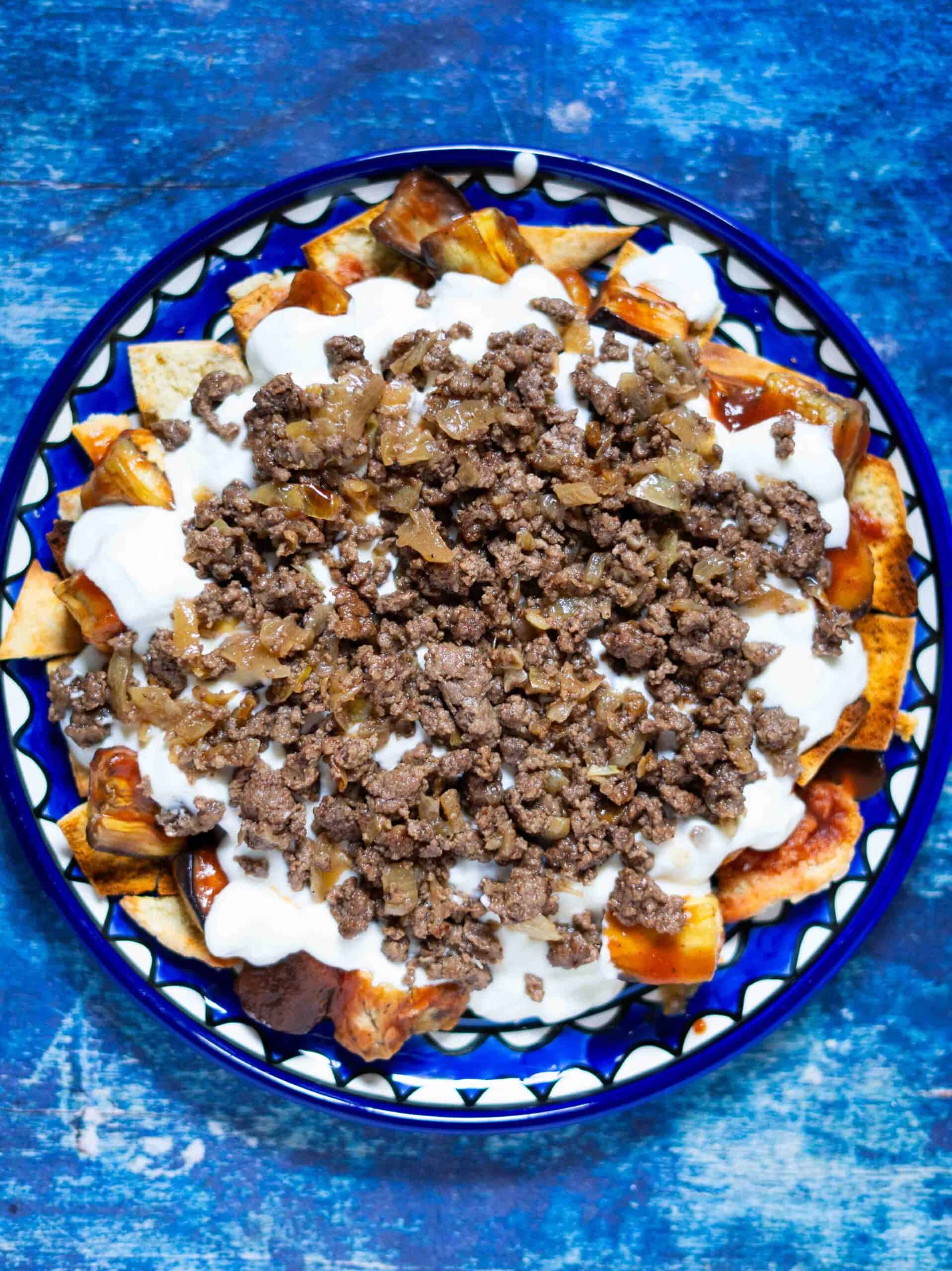 Ground meat on top of yogurt, bread and eggplants