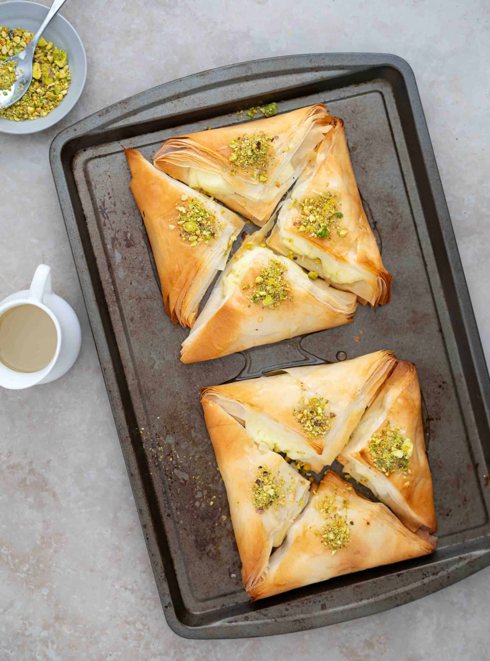 warbat on a tray after baking drizzled with sugar syrup and added pistachios