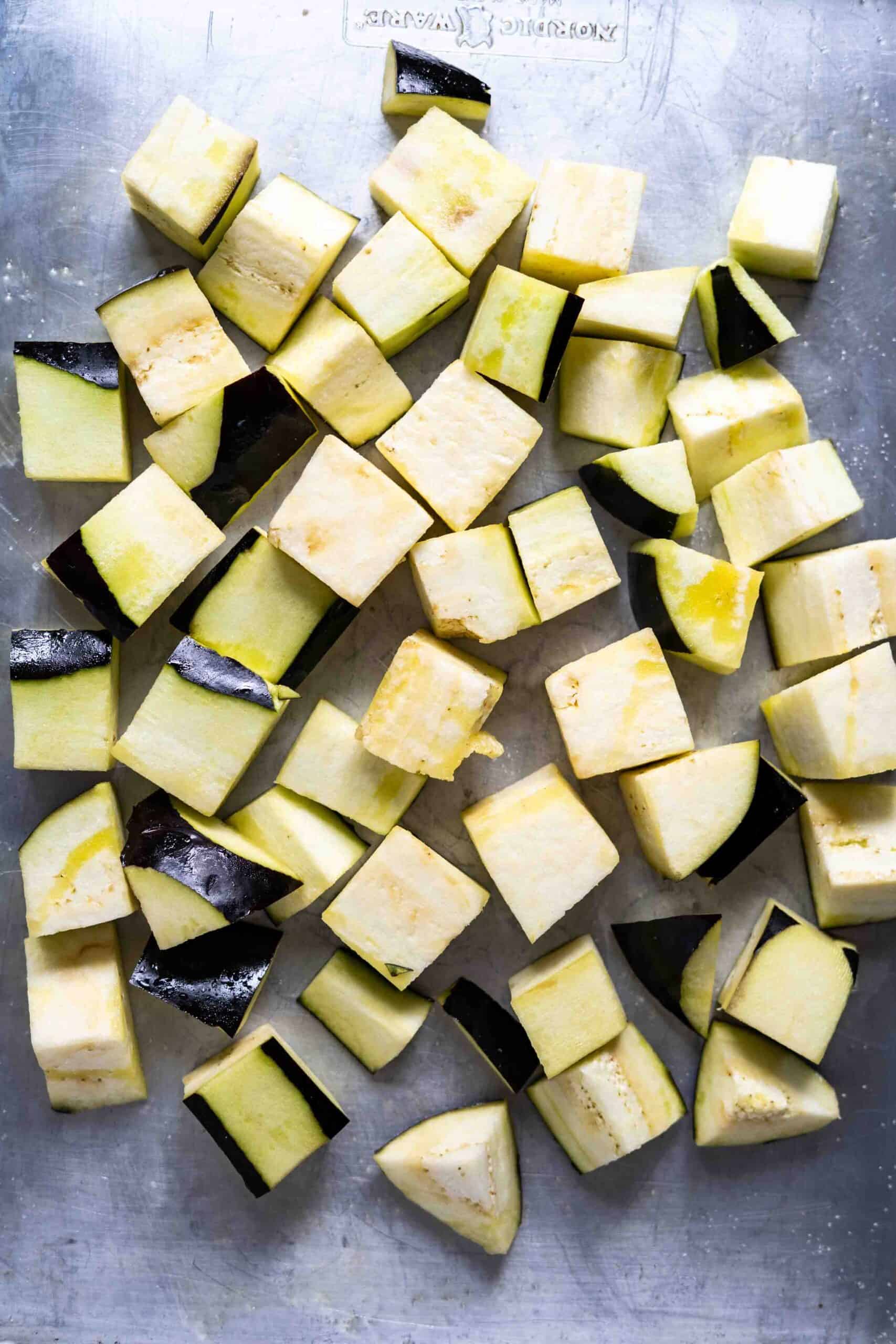 Eggplants sliced in cubes sprinkled with oil on a baking sheet prior to roasting