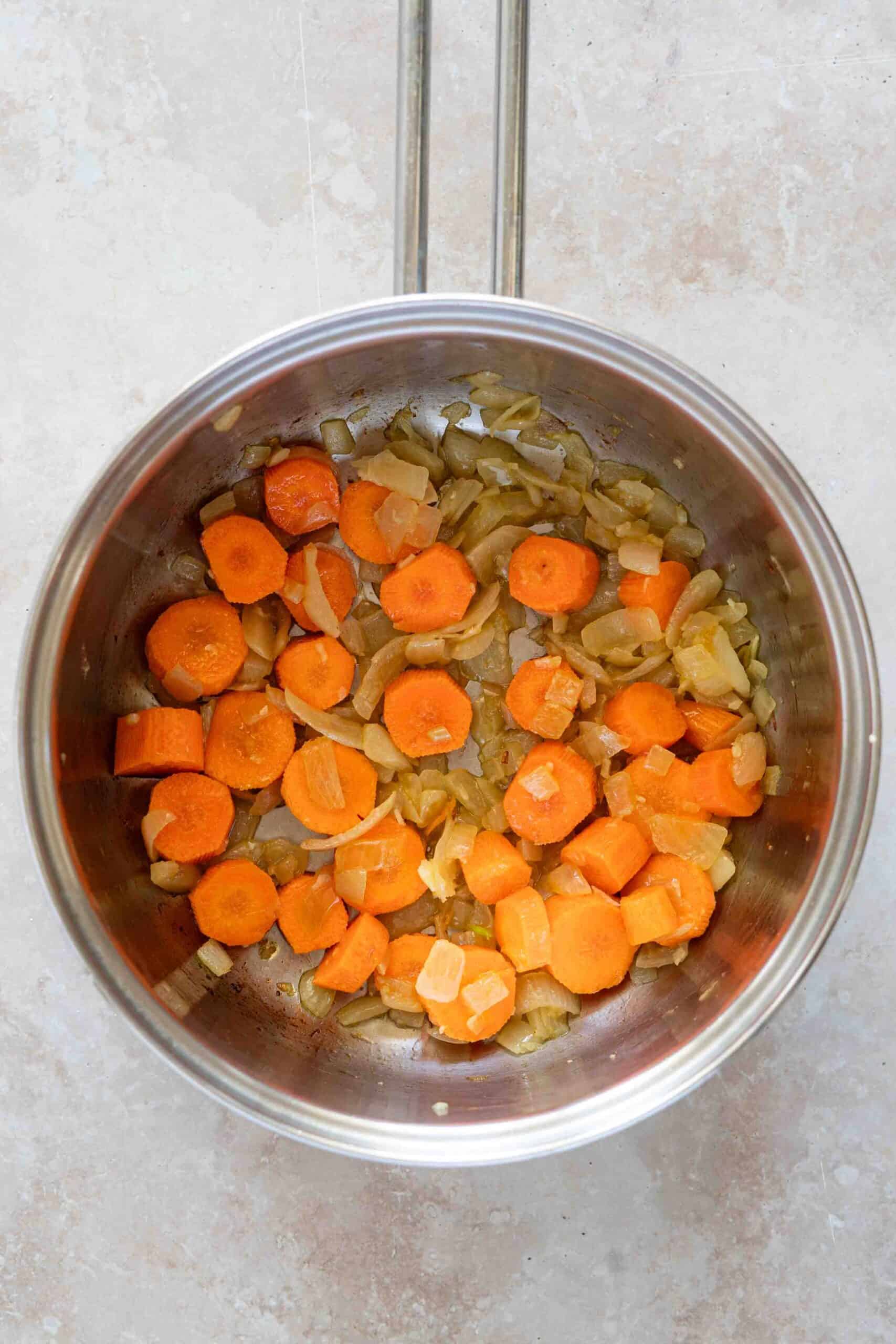 Sliced arrots over onions in a pot