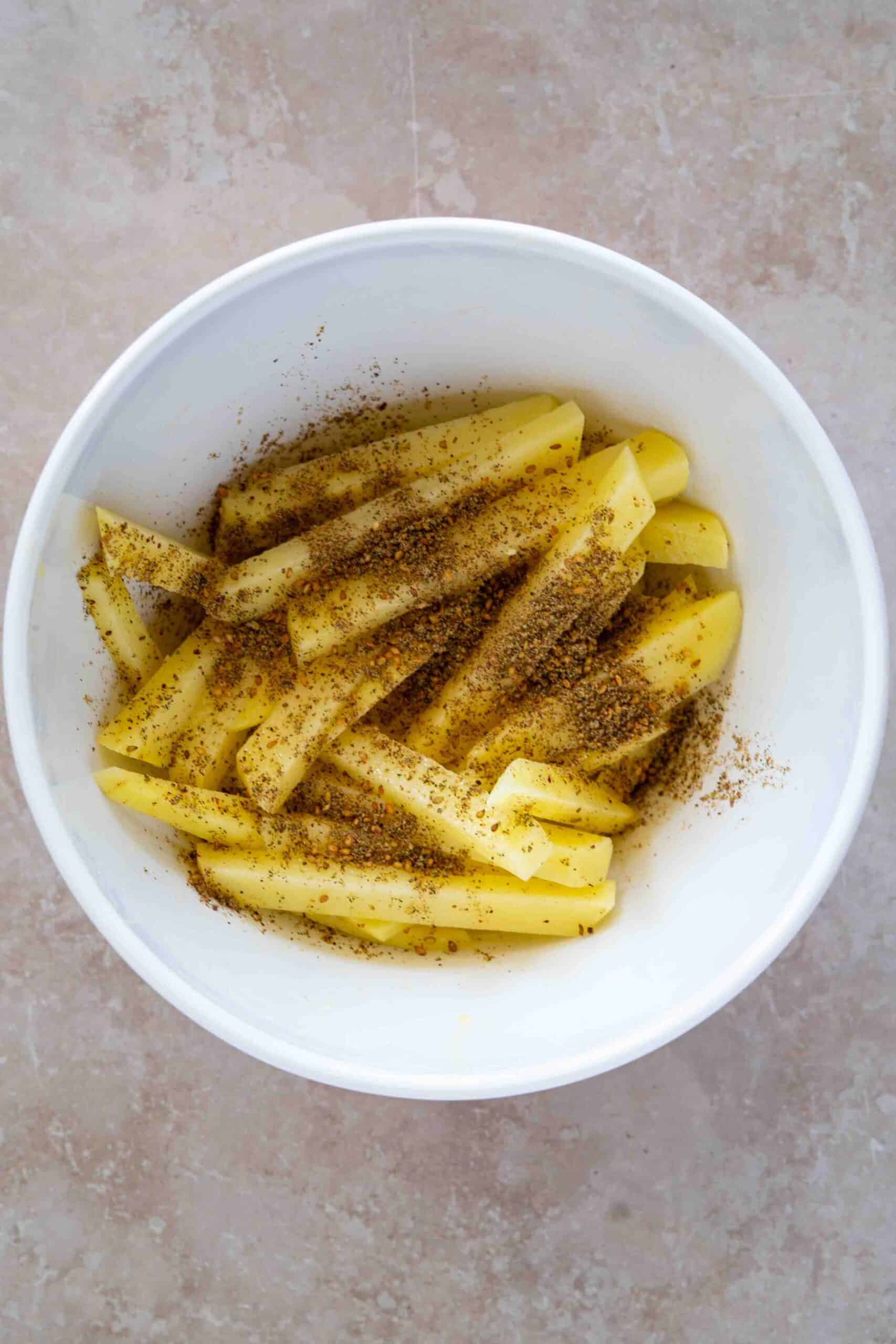 Sprinkling zaater over potatoes
