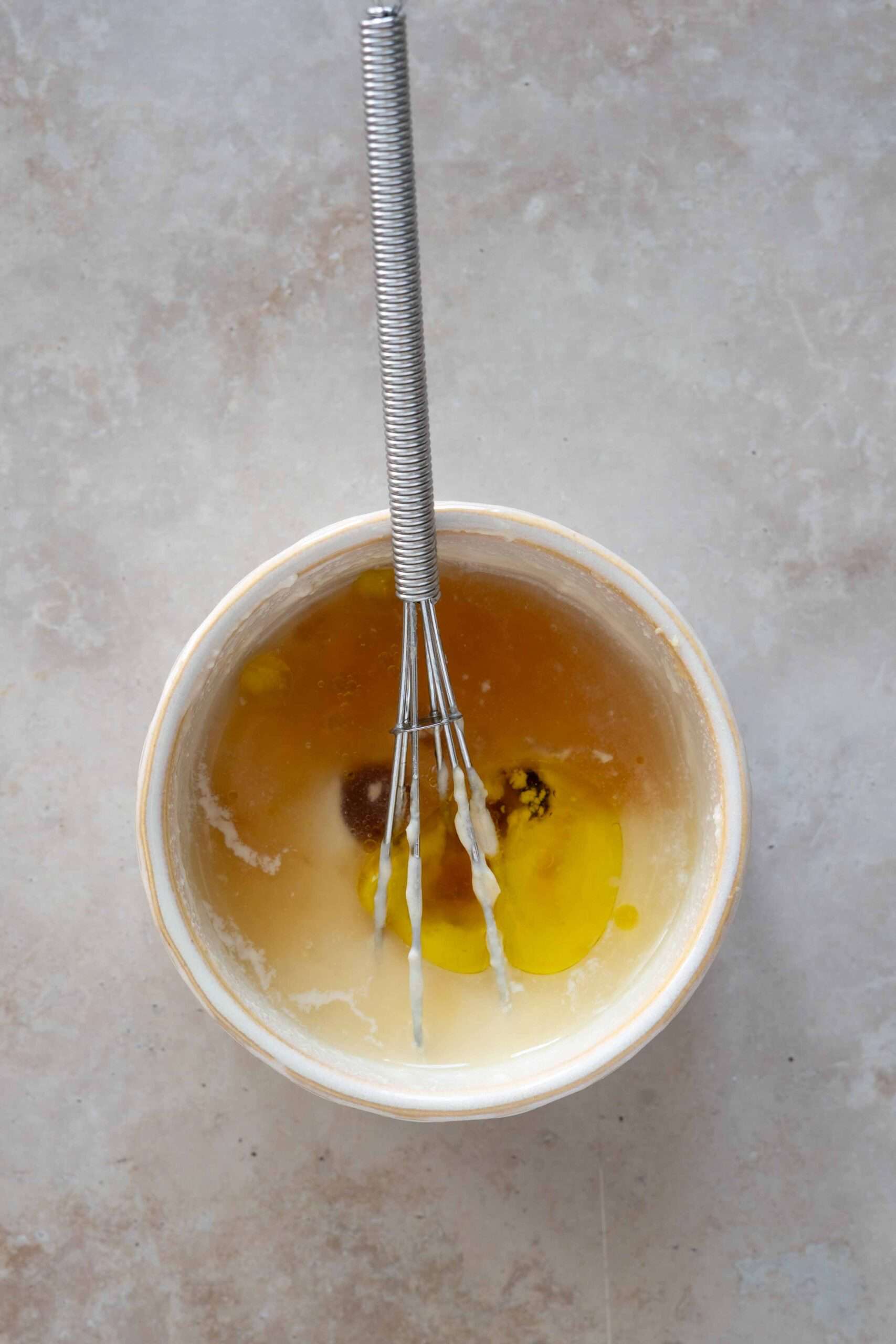 adding olive oil, salt, vinegar and maple syrup over tahini and water mixture
