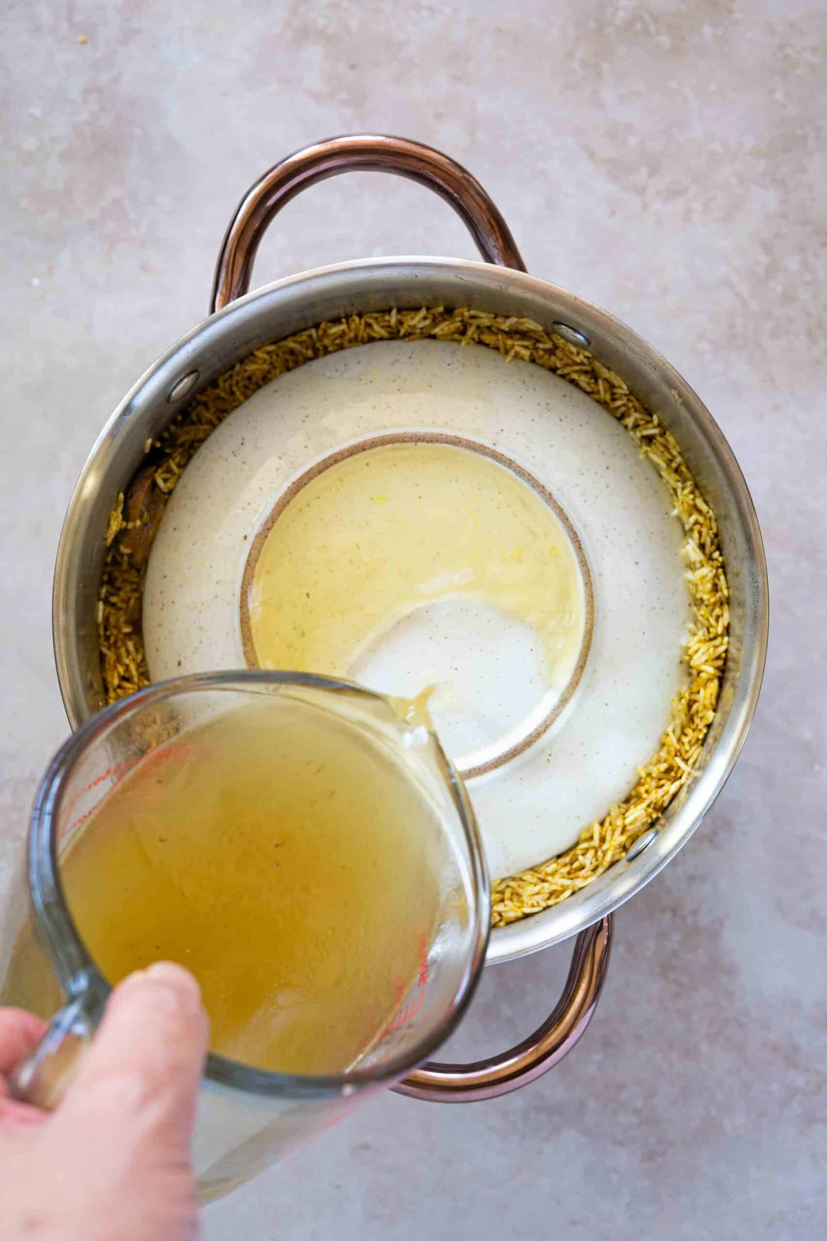 Pouring chicken broth over rice in pot
