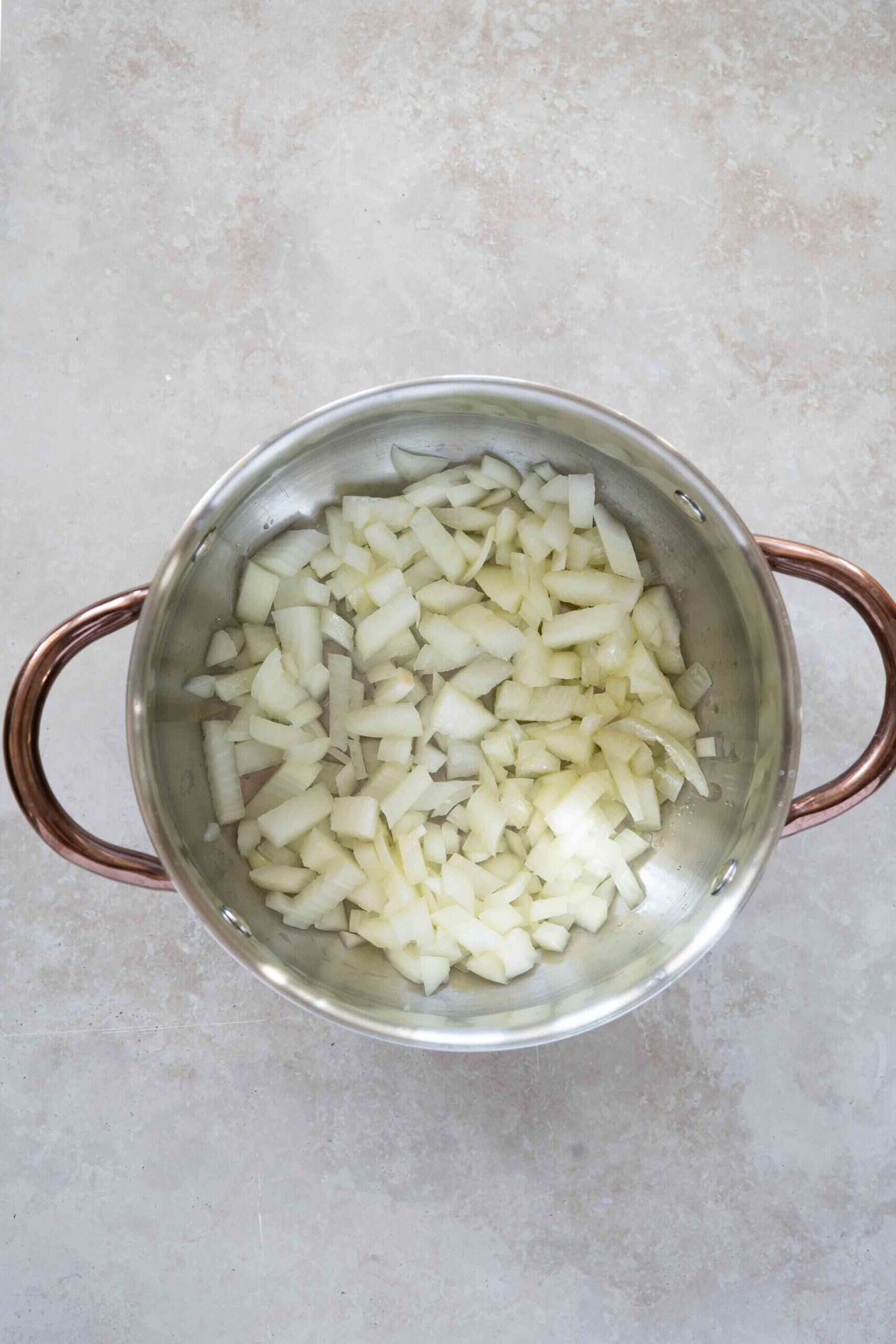 Chopped onions over oil in a pot ready for sautéing.