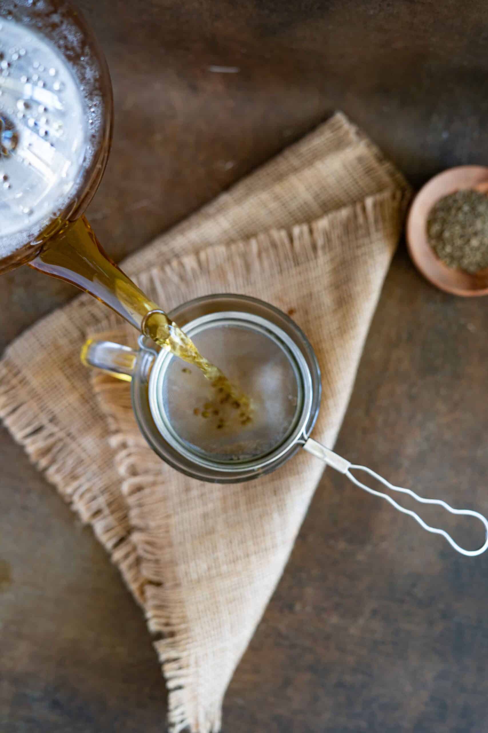 Pouring anise tea into a cup using a strainer