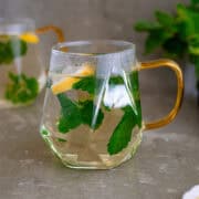 Hot mint tea in a glass with slices of lemon and fresh mint leaves