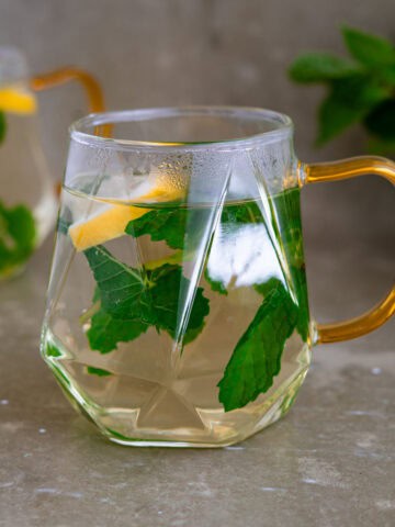 Hot mint tea in a glass with slices of lemon and fresh mint leaves