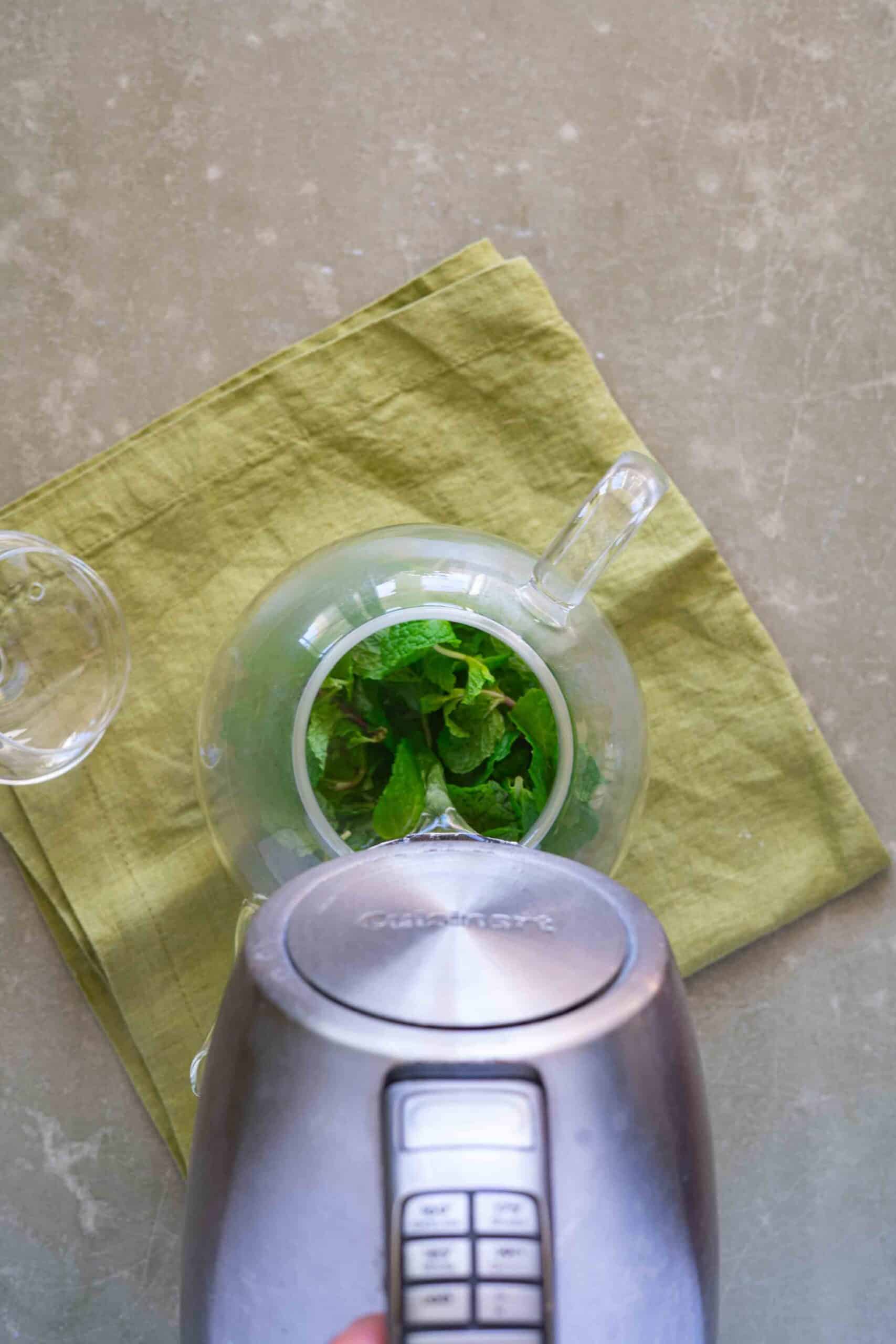 Pour hot water from an electric kettle over the fresh tea leaves in a teapot.