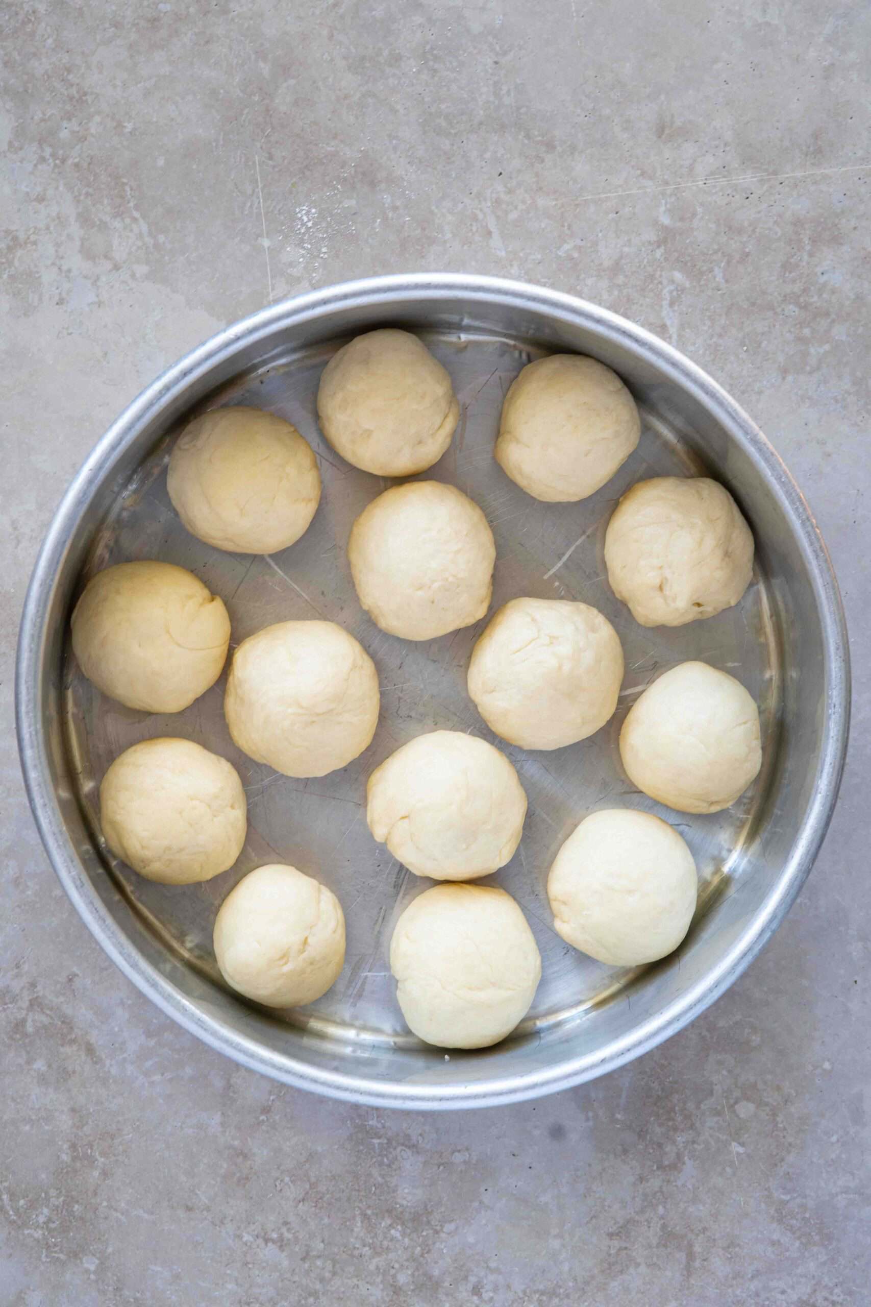 Dough cut into rounded pieces (about 1-2") and arranged in a round tray, before resting.