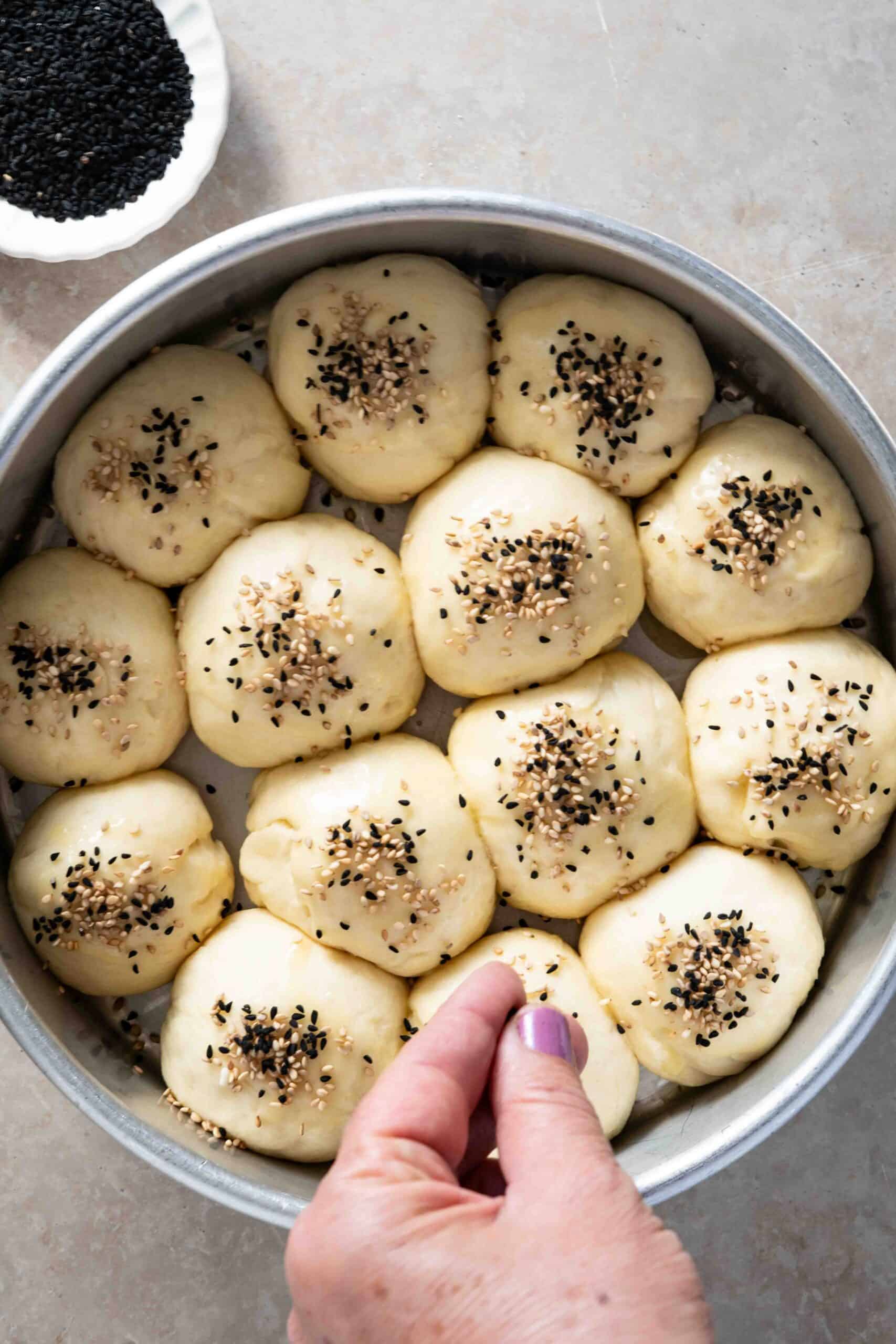 sprinkling sesame and nigella seeds over dough pieces before baking.
