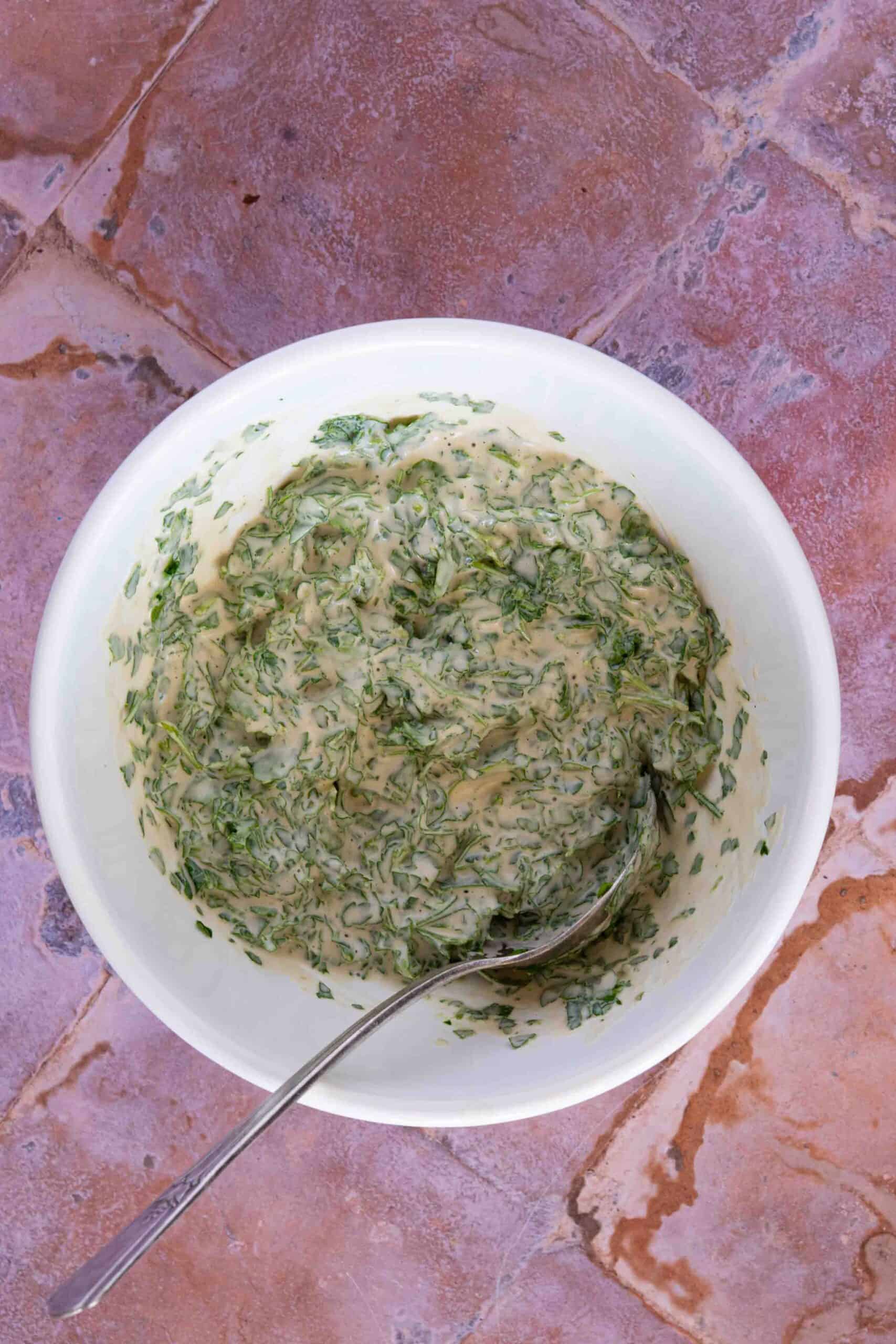 Mixing tahini sauce with chopped parsley