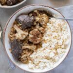 Cauliflower stew with lamb next to rice on a plate - featured photo