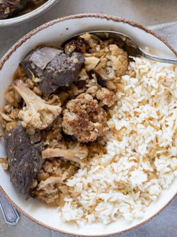Cauliflower stew with lamb next to rice on a plate - featured photo