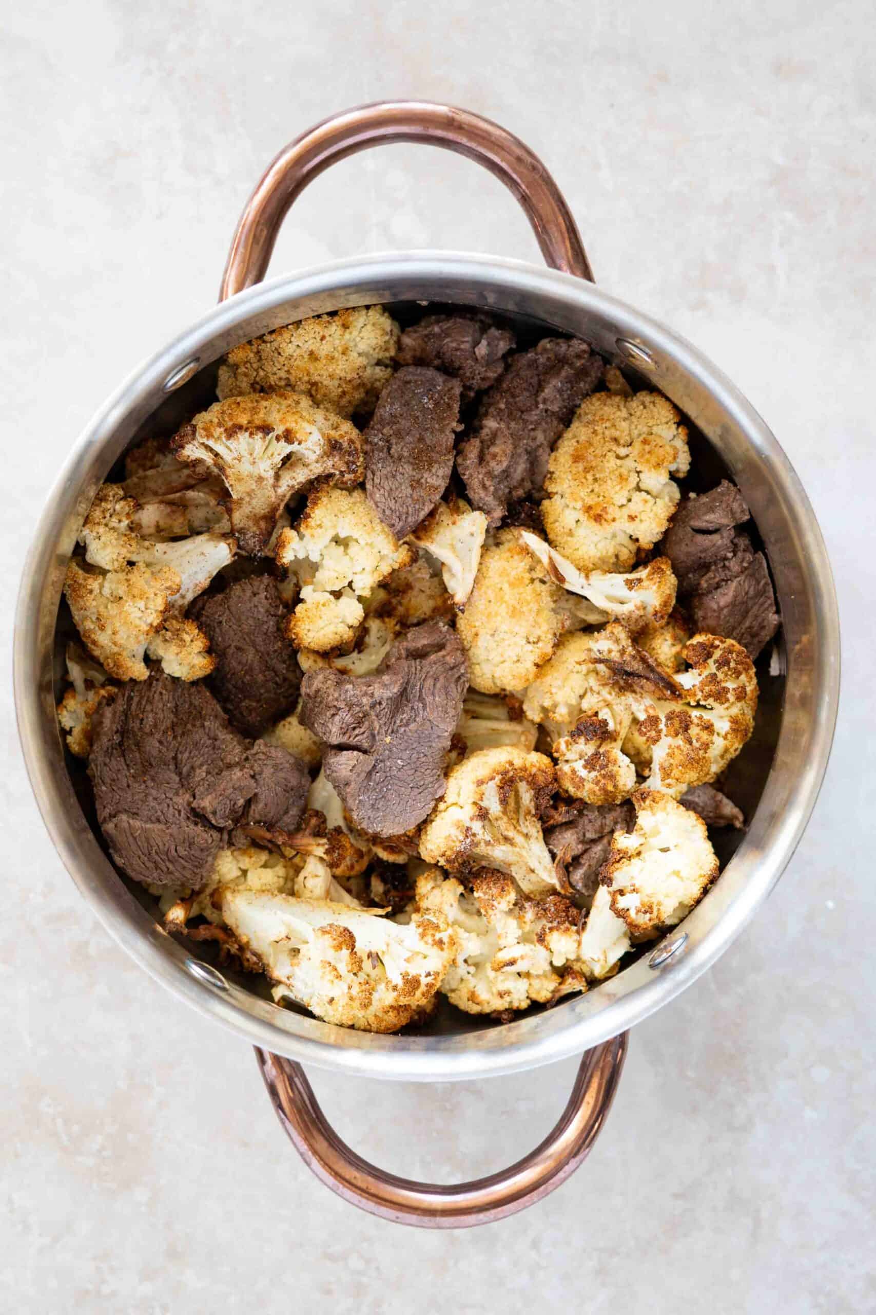 Grilled cauliflowers and lamb chunks in a pot.