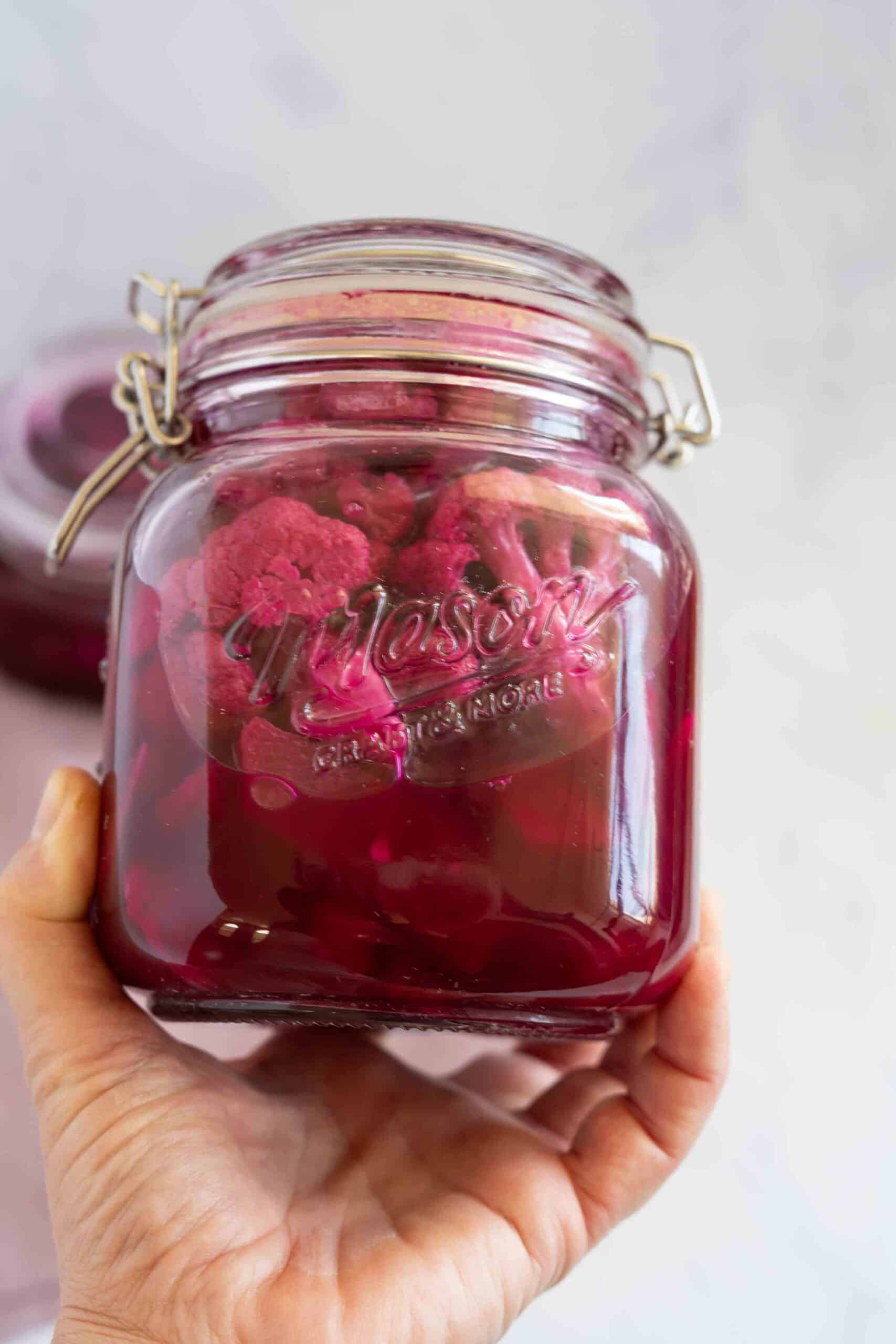 Holding a jar of pickled cauliflower.