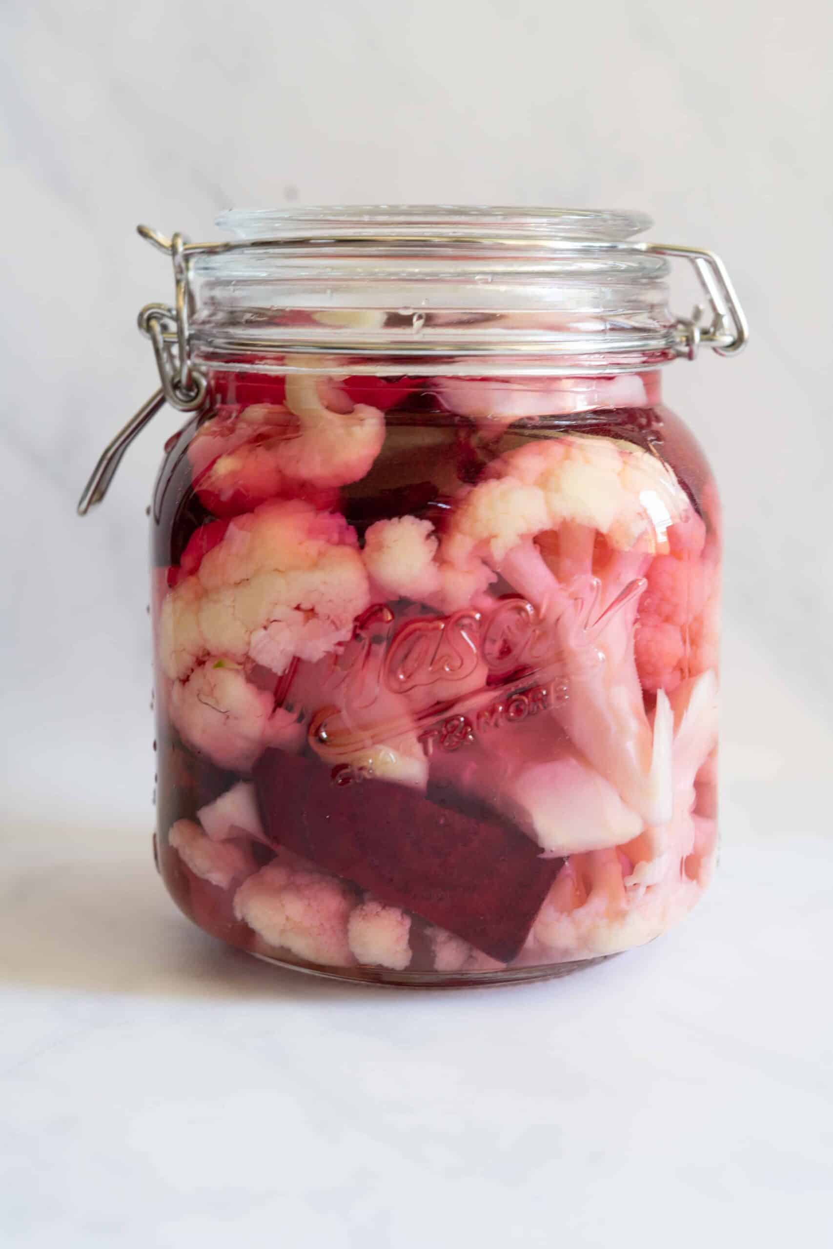 A jar sealed filled with cauliflower, some raw beets ready for picklin.