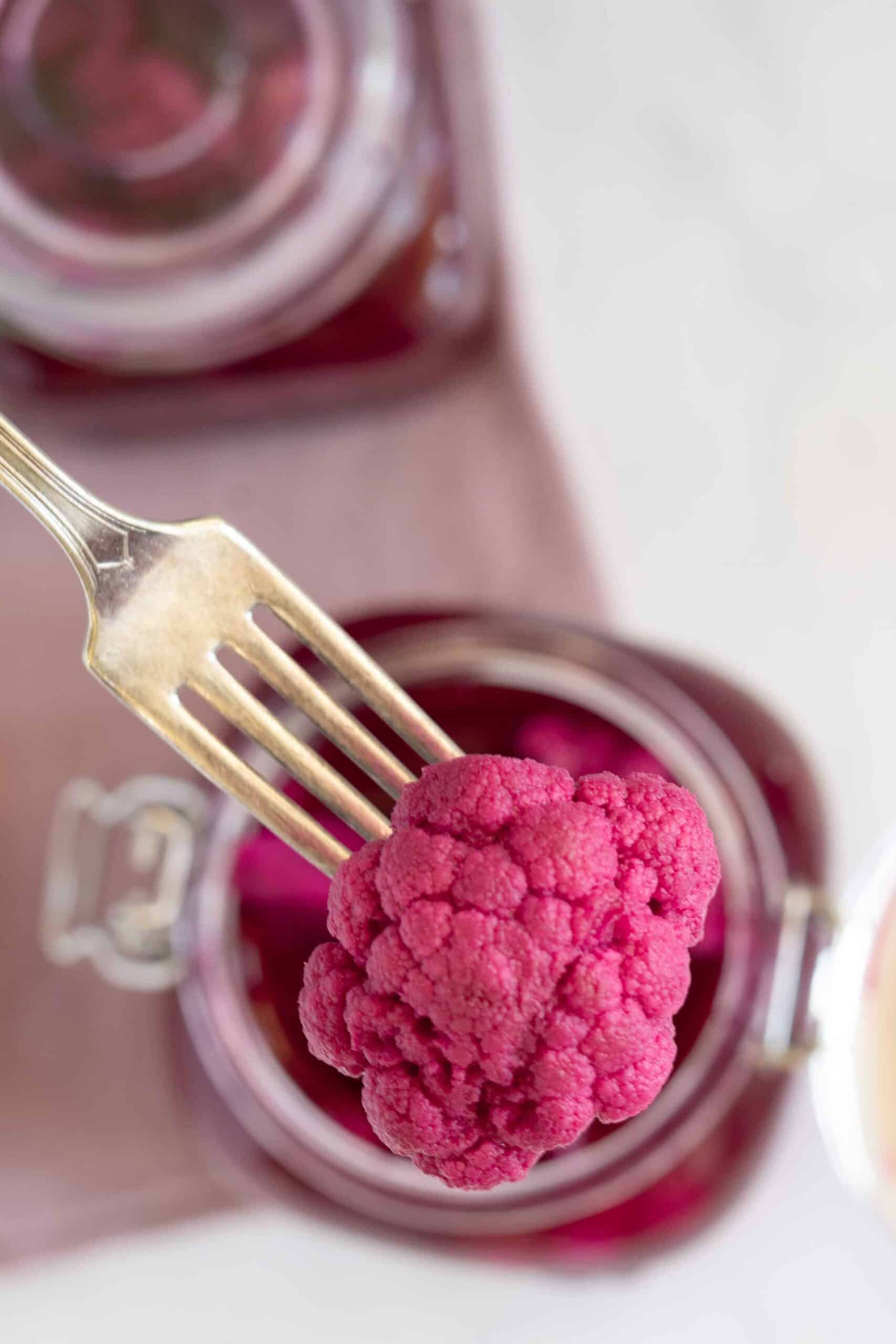 Picking one pickled cauliflower florets with a fork.