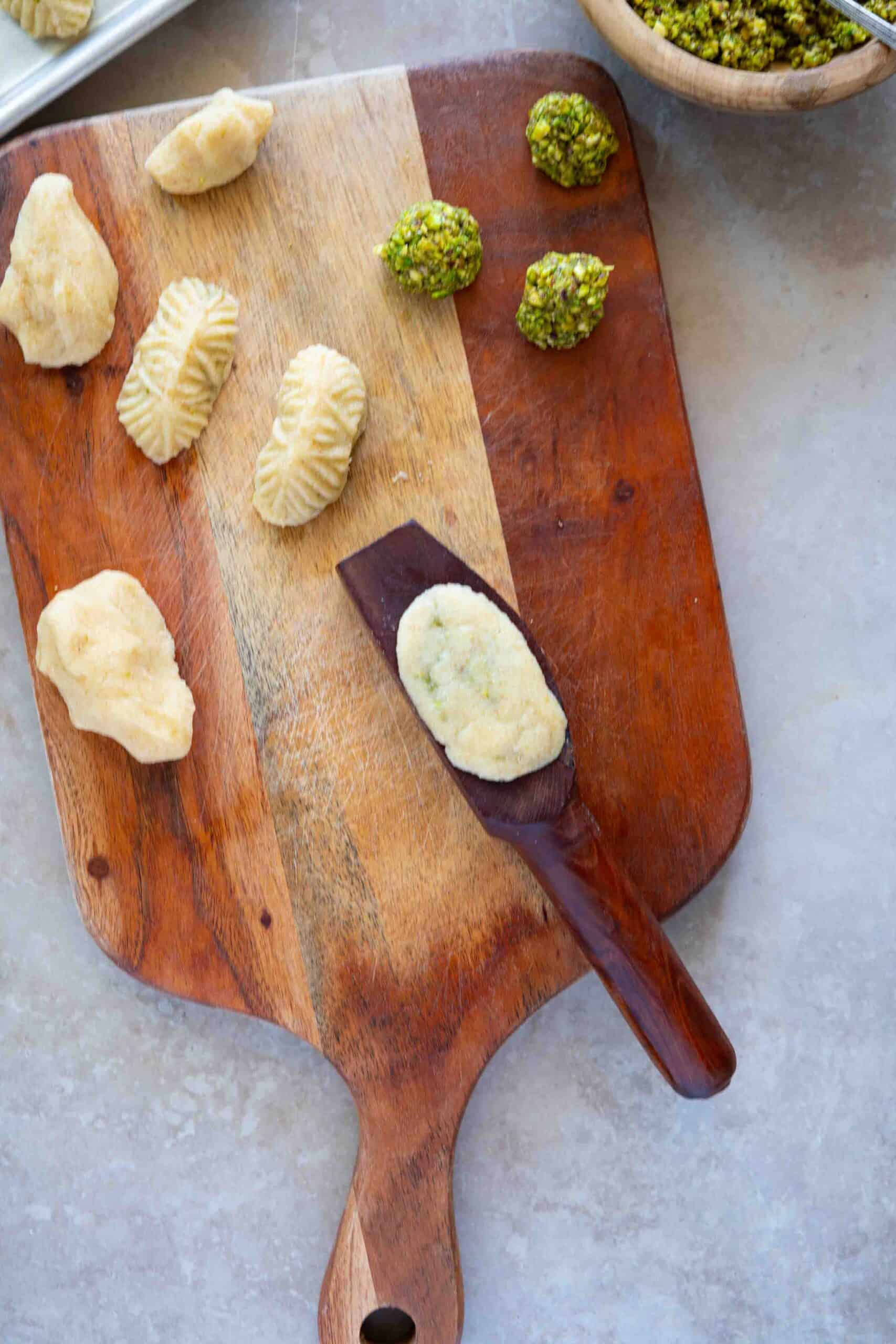 Step 2: Bring the dough together over the pistachio filling to seal it, then flip the mold and gently tap it on the table so the cookie releases from the mold.