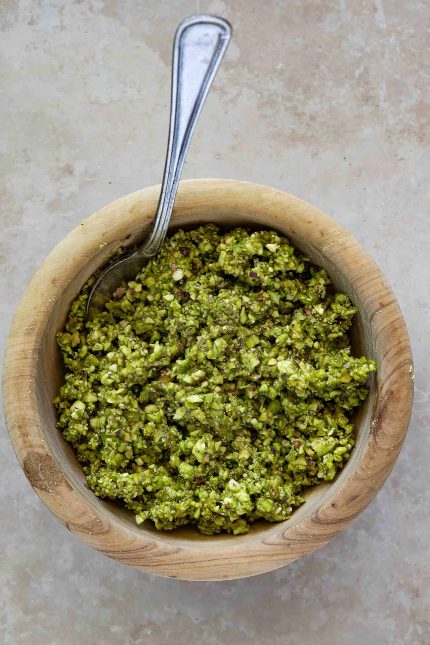 Pistachio mixture in a small bowl, pistachios, sugar syrup and orange blossom water.
