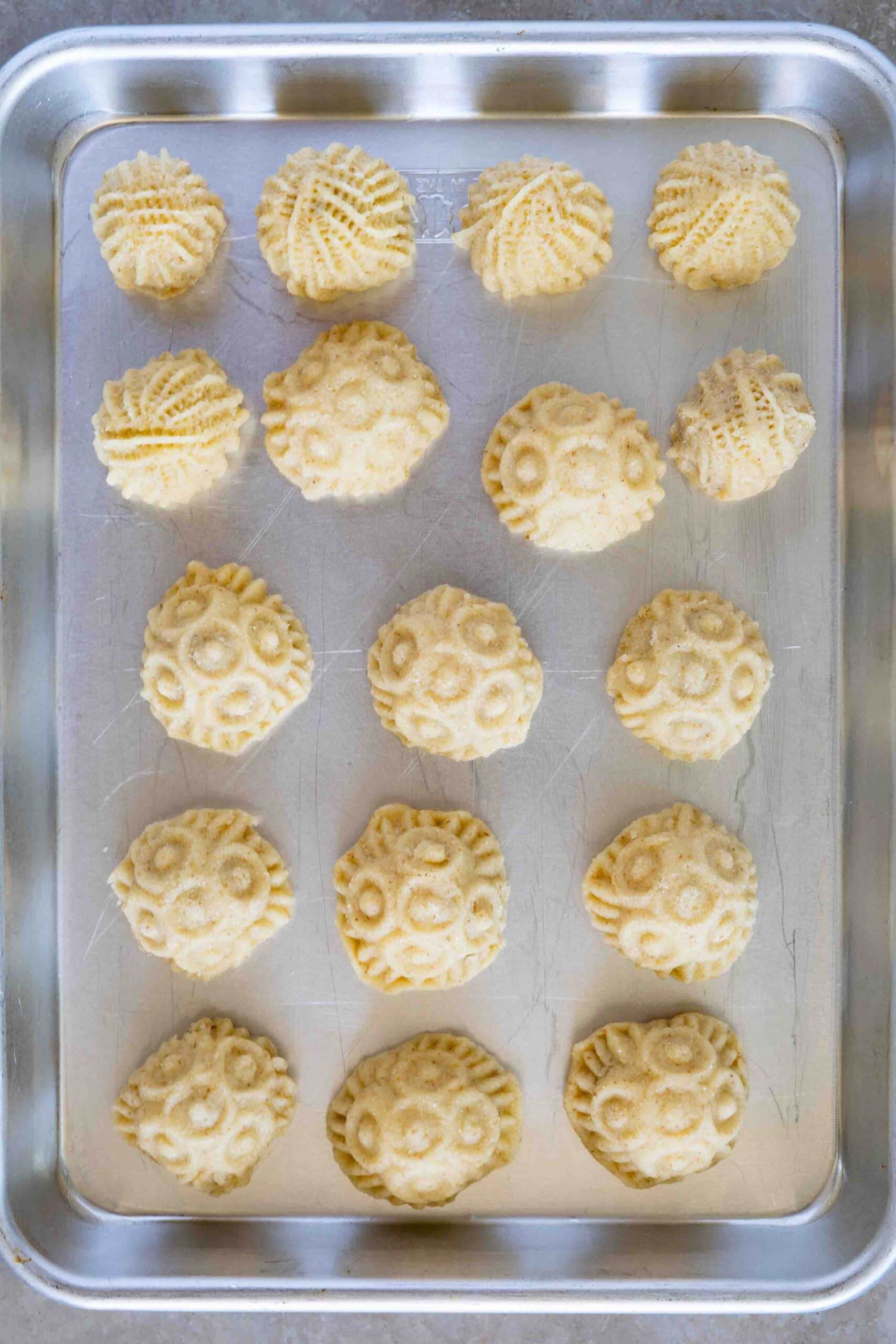Decorated maamoul cookies in a baking sheet ready for baking.