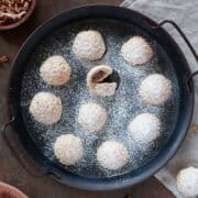 A close up photo for a rounded serving tray filled with maamoul, dusted with powdered sugar.