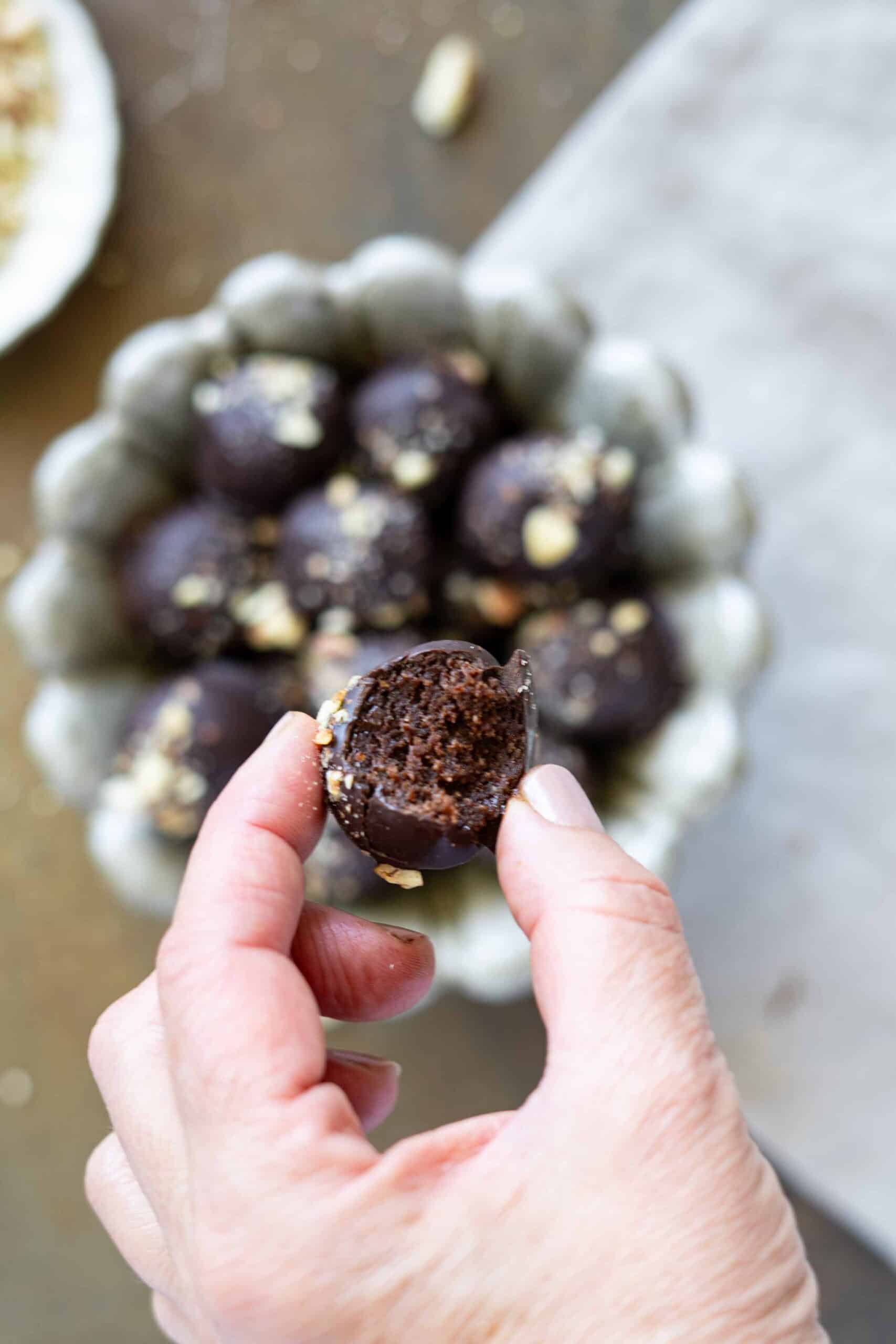 Holding a tahini chocolate ball with a bite taken out of it.
