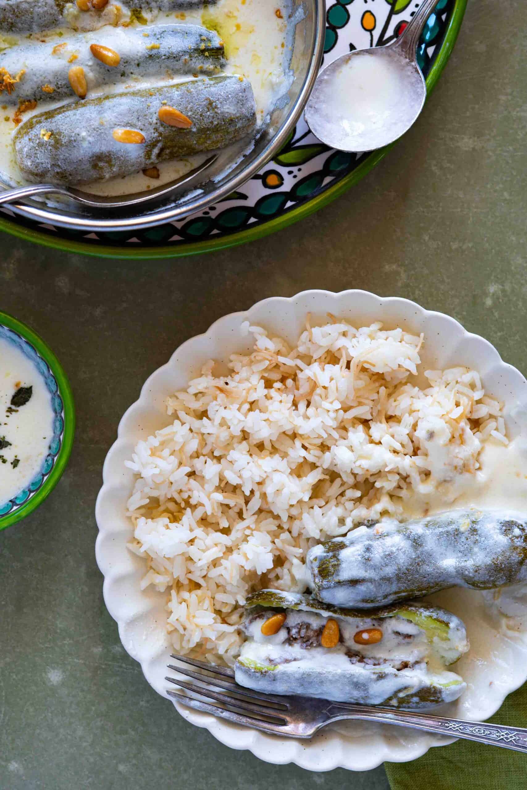 Kousa Bil Laban served on a plate with a side of vermicelli rice, featuring traditional Palestinian stuffed zucchini in a creamy yogurt sauce.