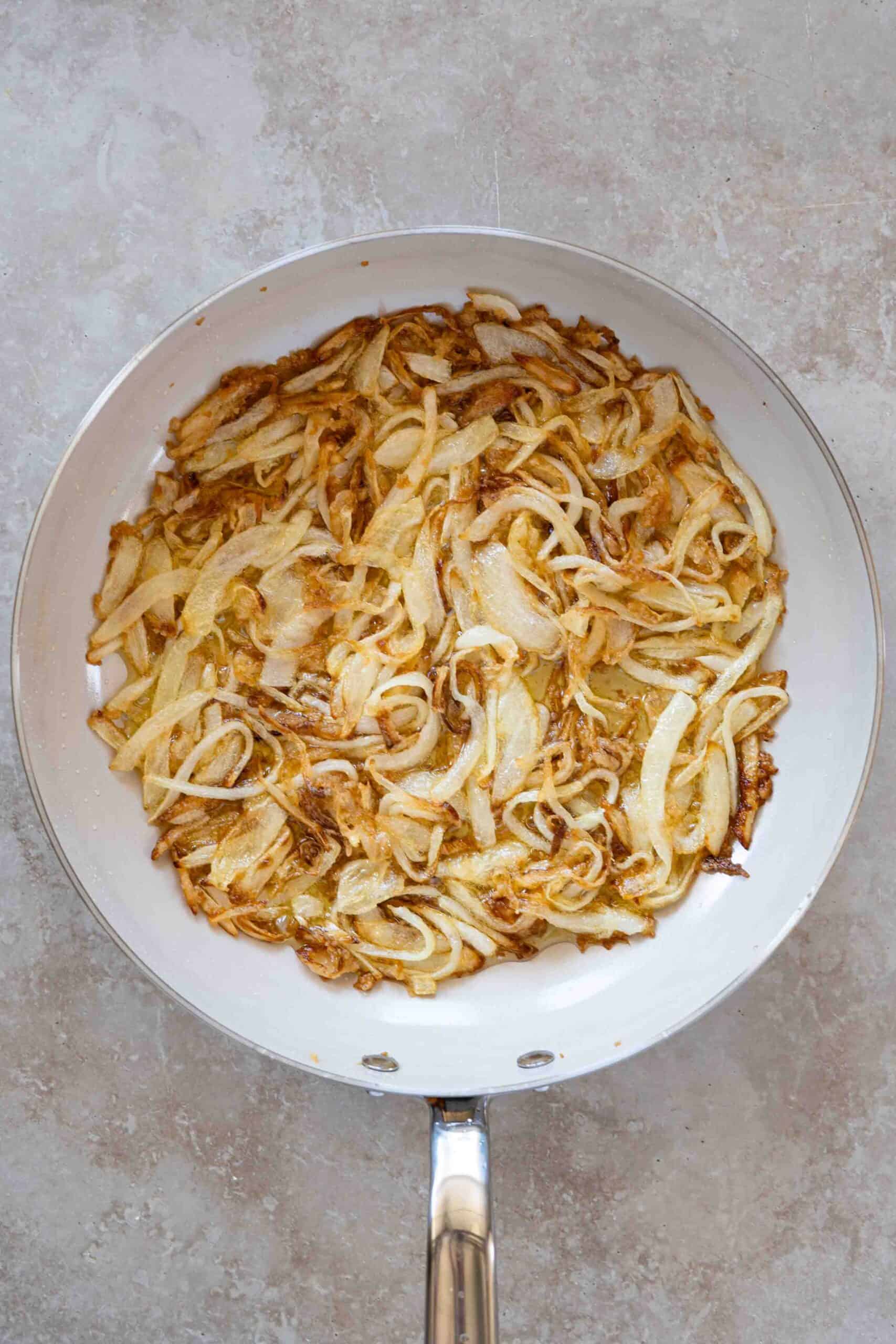 Golden caramelized onions in a skillet after cooking in olive oil.