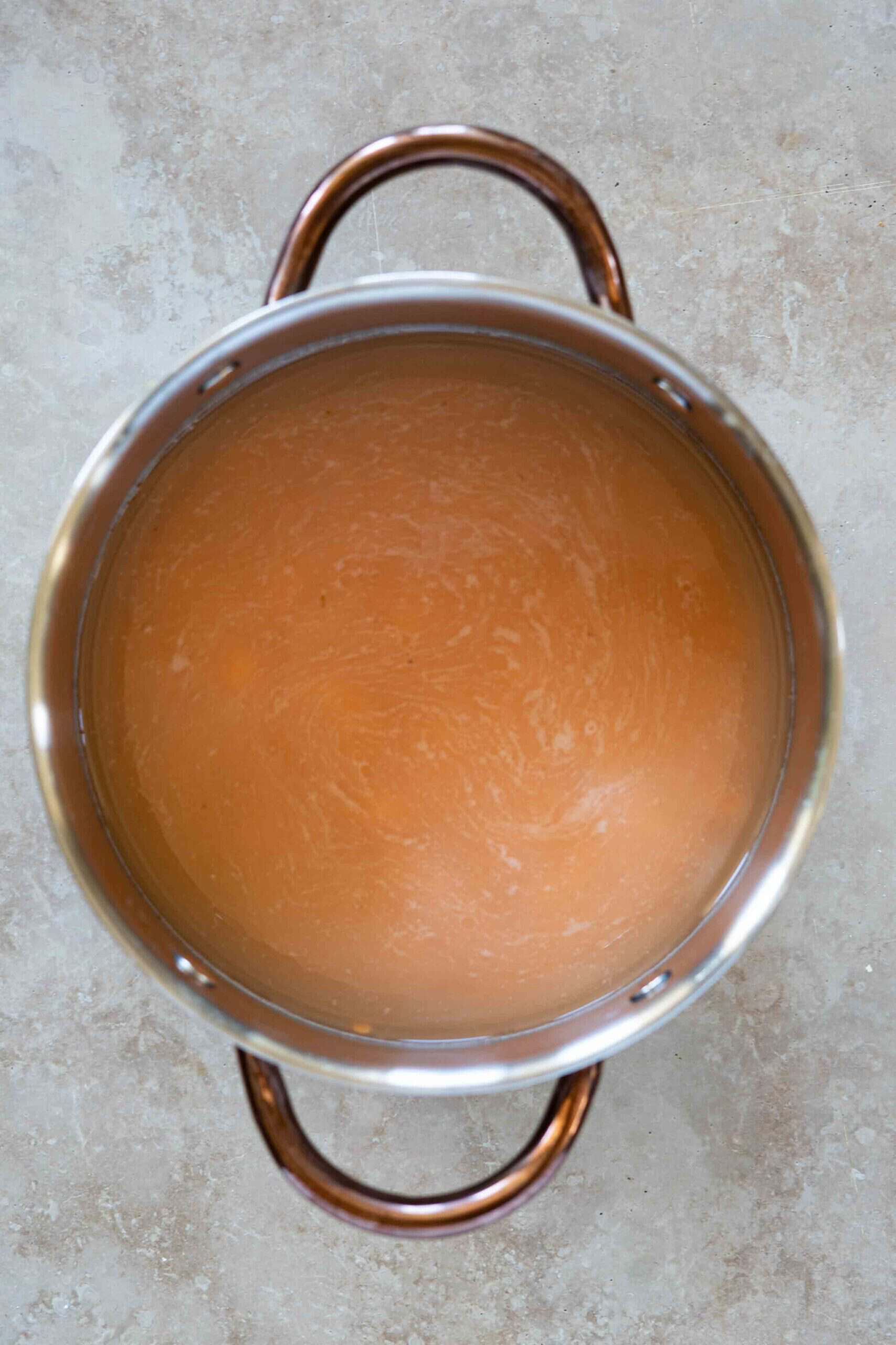 Red split lentils covered with water in a pot before cooking.