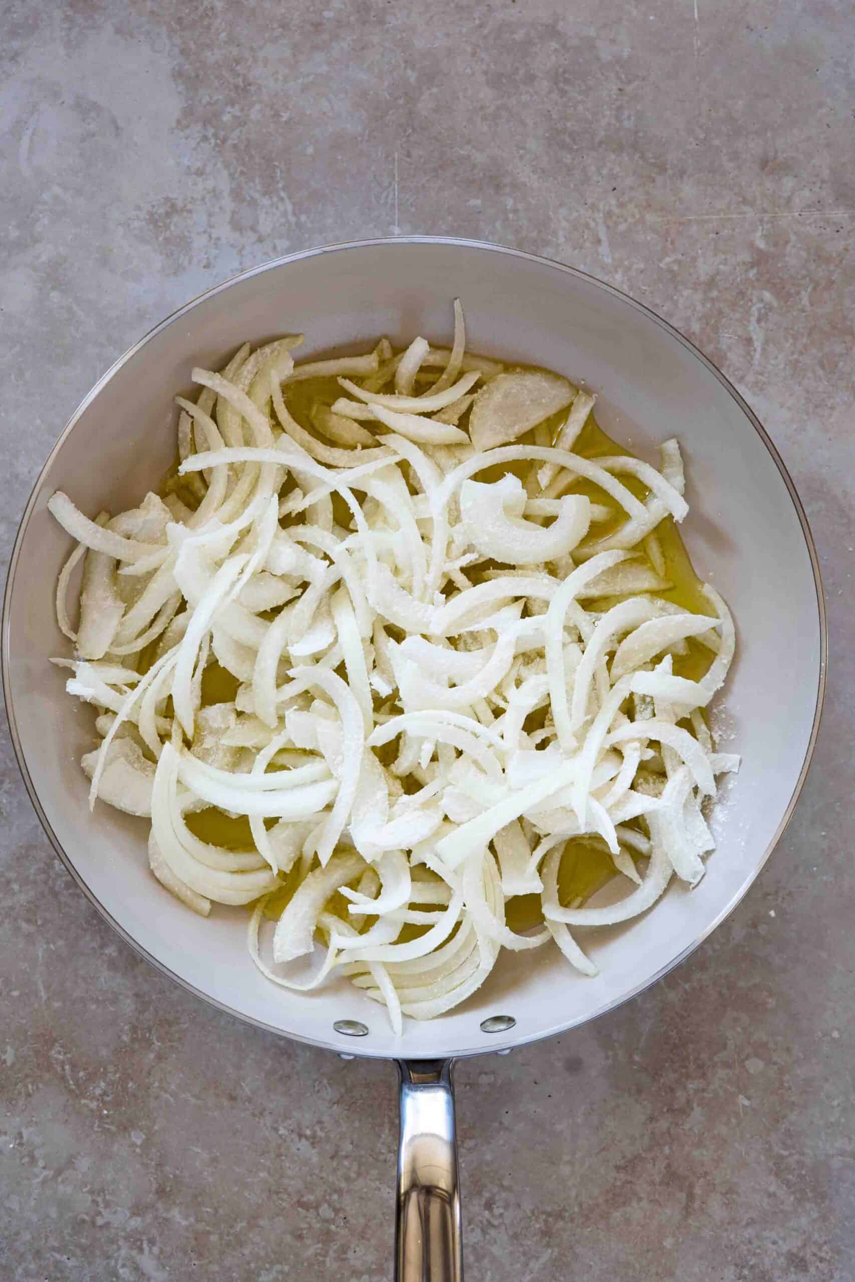 Thinly sliced sweet onions in olive oil in a skillet before caramelizing.