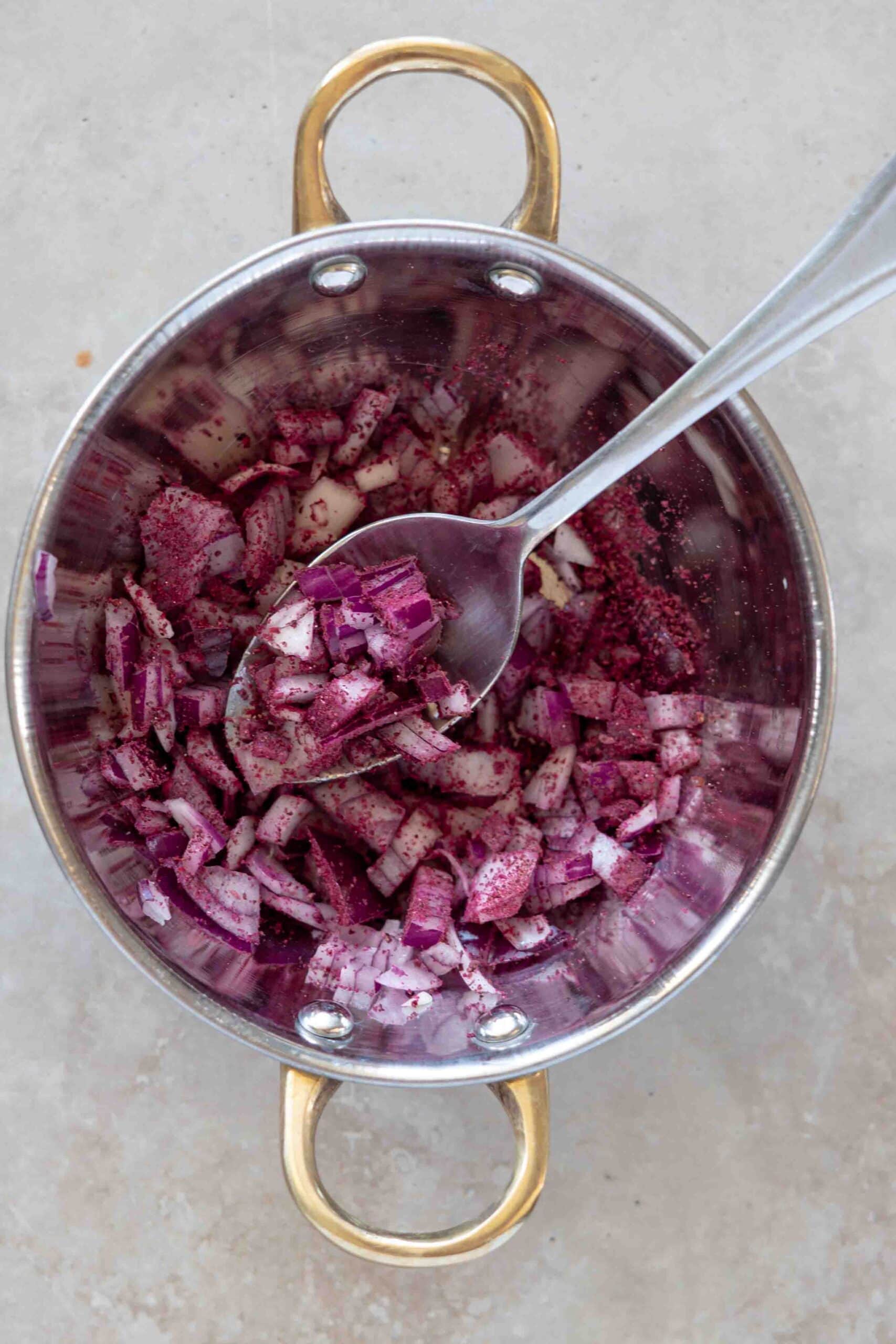 Finely chopped red onions mixed with sumac powder in a bowl