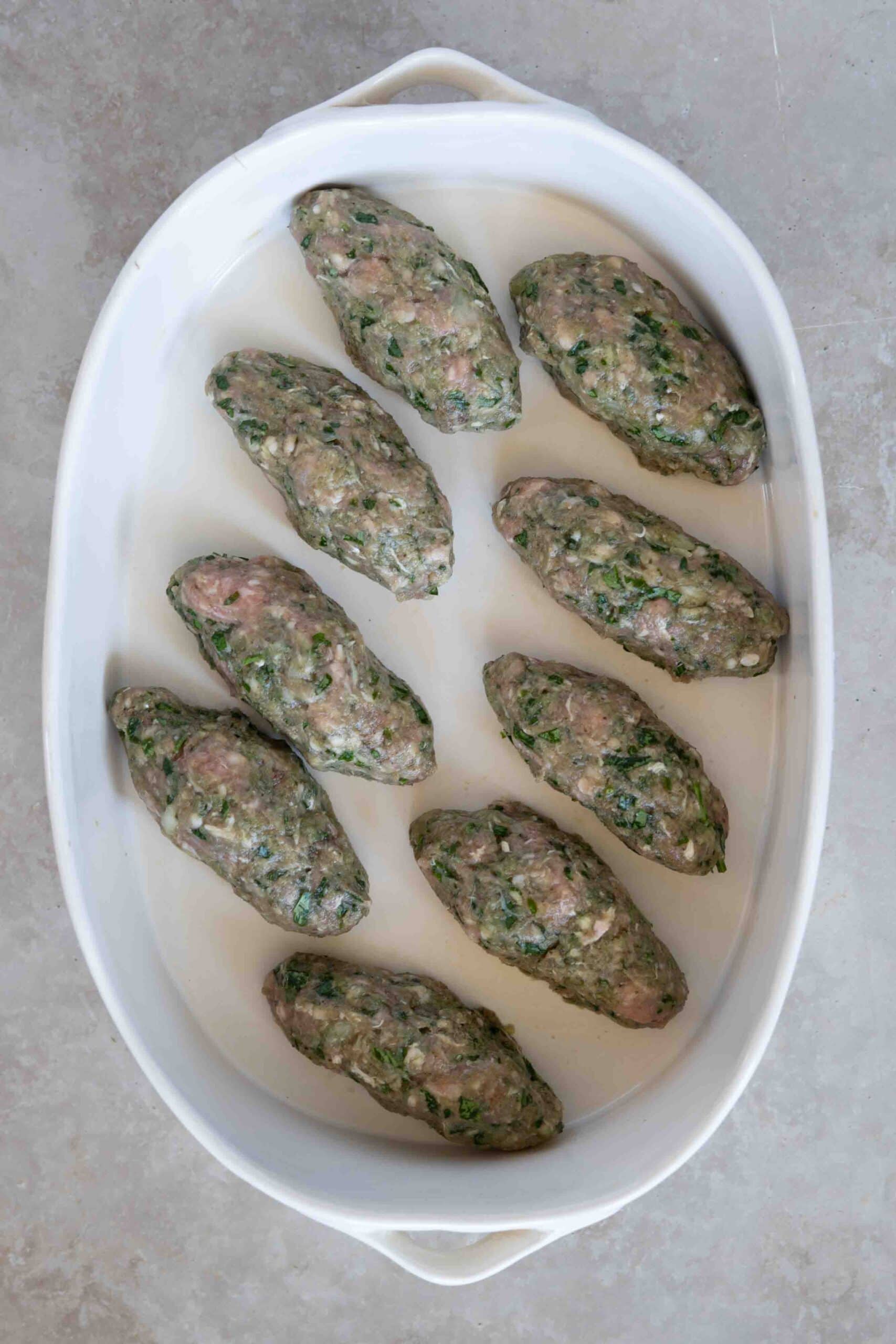 Oval shaped kafta arranged in baking dish