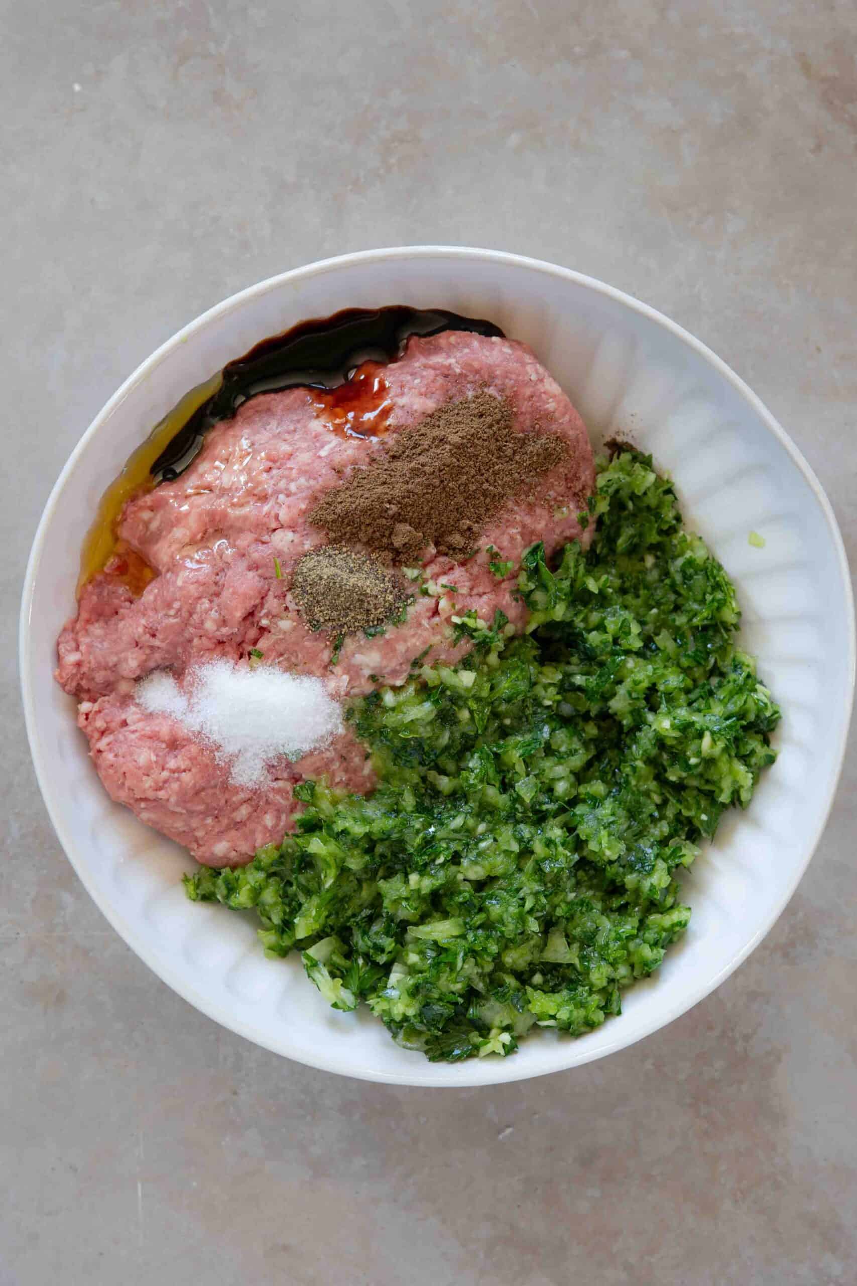 Ground meat, parsley, pomegranate molasses, olive oil, salt and spices in a bowl.