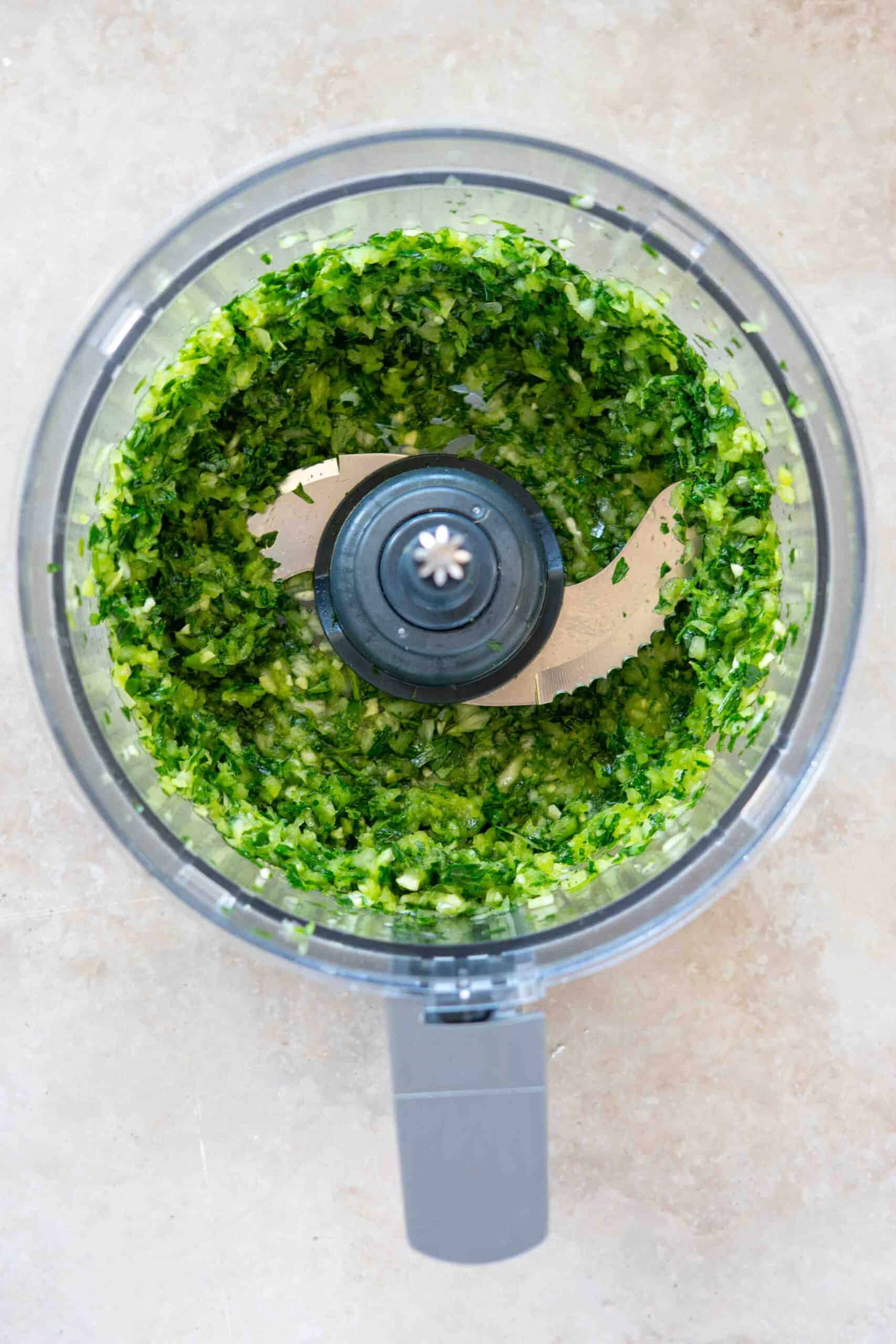 Onions, garlic cloves and parsley leaves processed into paste in a food processor.