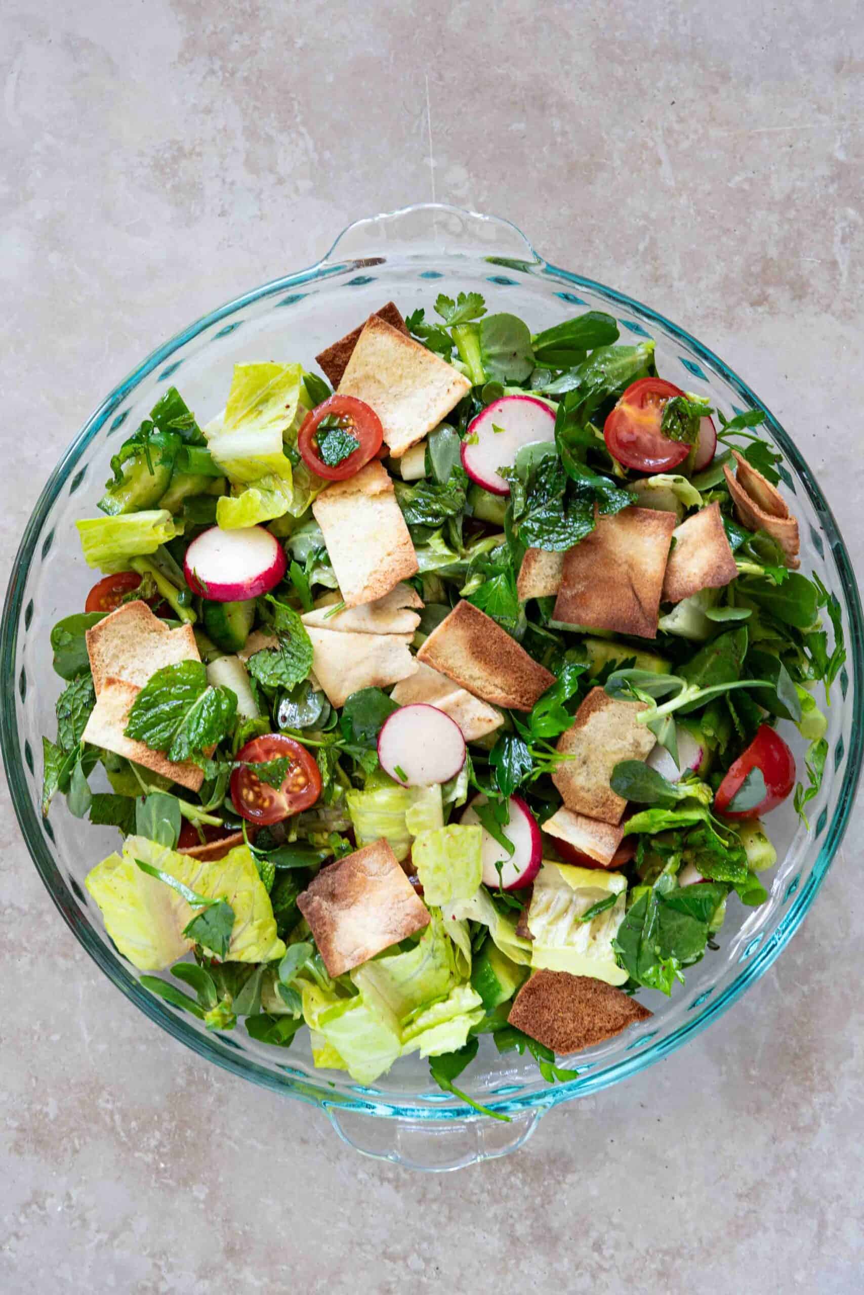 Fattoush salad mixed in a bowl with toasted arabic bread.