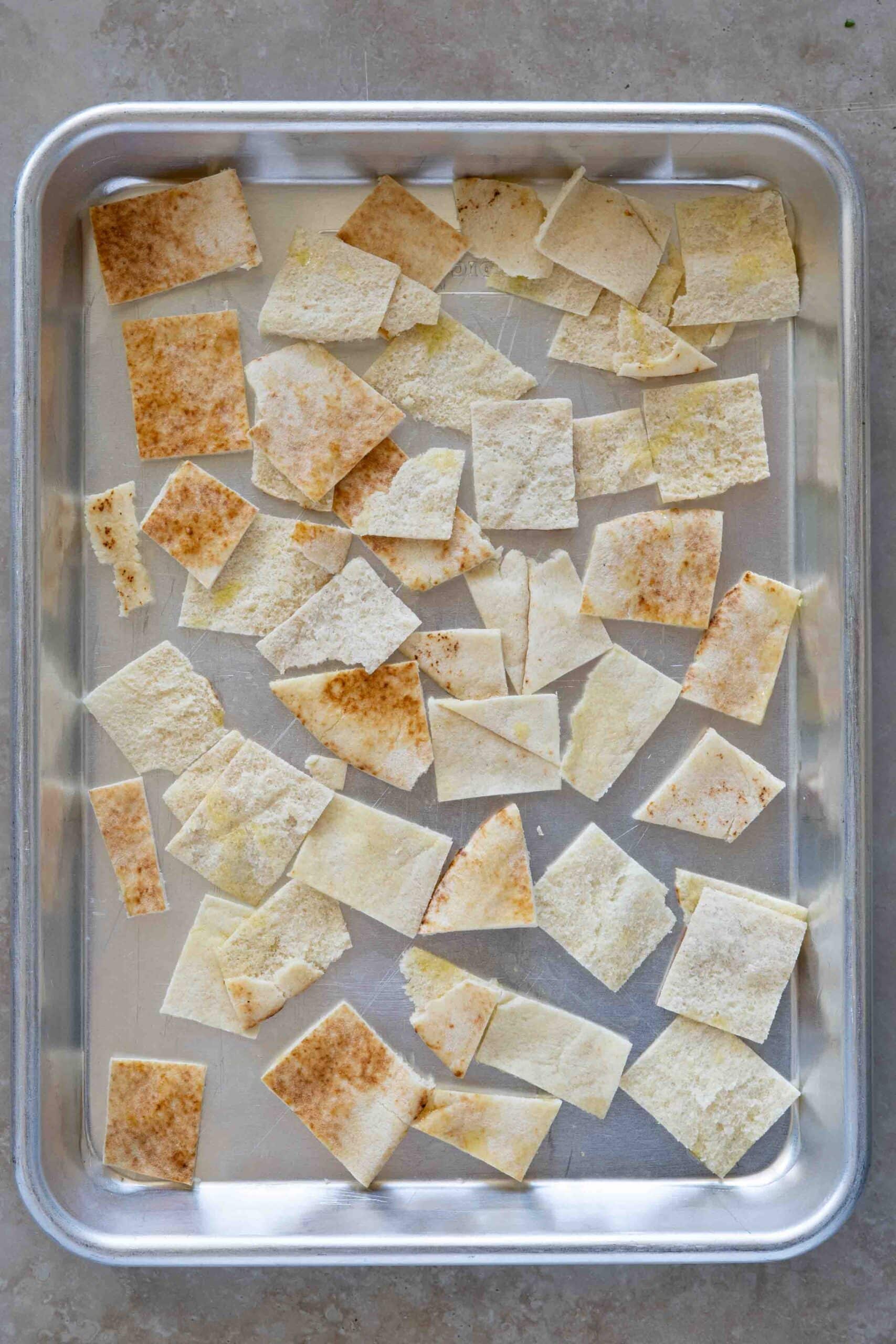 Flat bread sliced into cubes place on a baking tray before toasting.