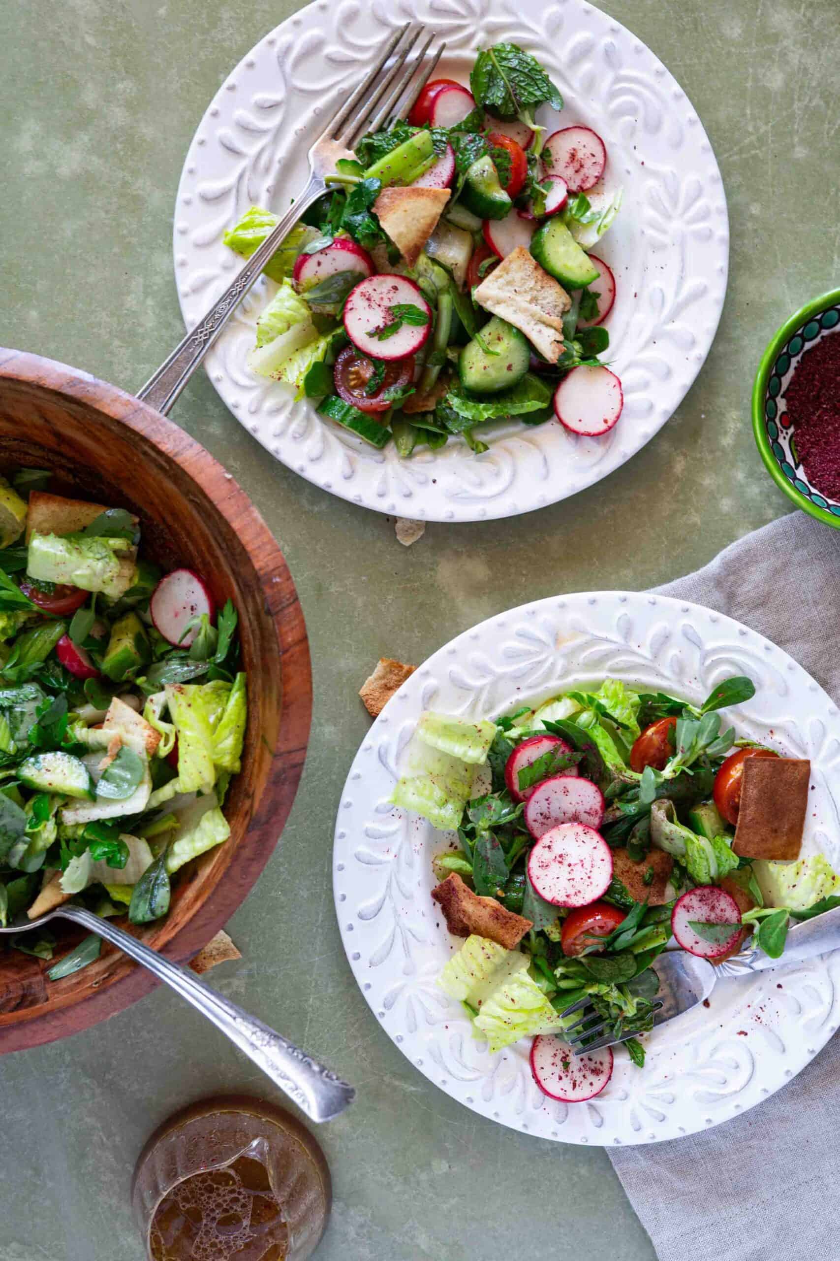 Fatoush salad place in serving plates, next to a bowl filled with authentic fattoush salad.