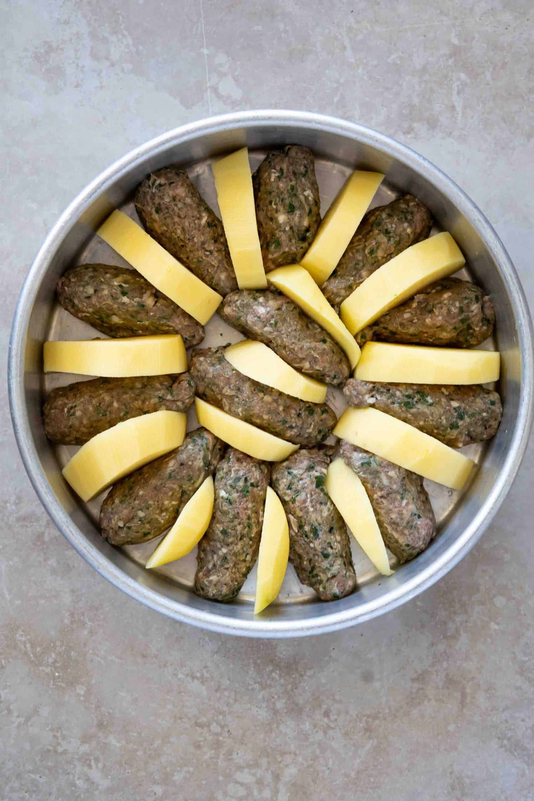 Kafta and potatoes in baking dish before baking