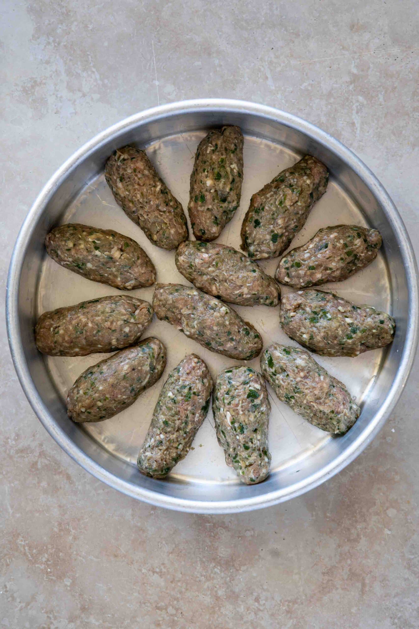 Oval-shaped kafta arranged in a baking dish before baking.