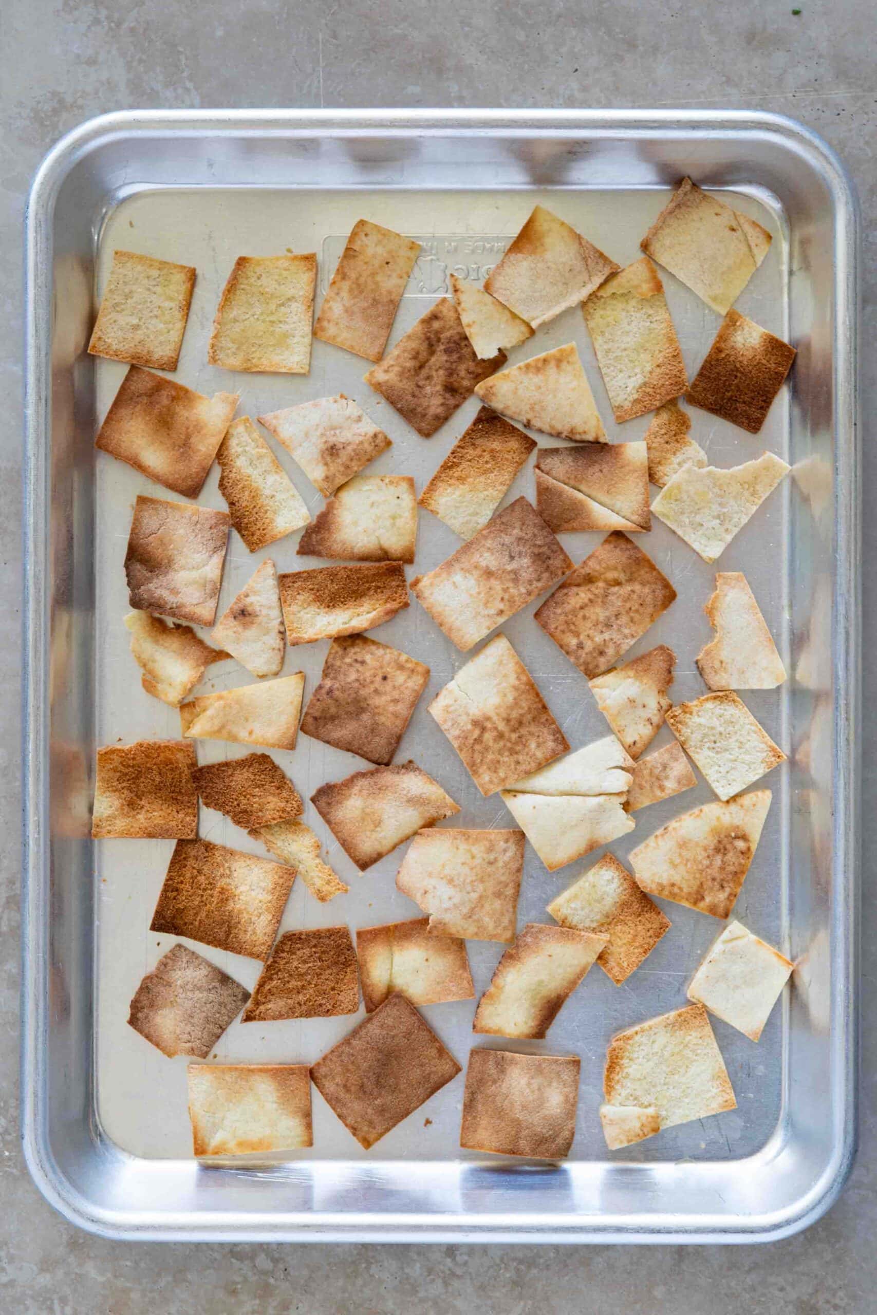 Flat bread sliced into cubes place on a baking tray after toasting.
